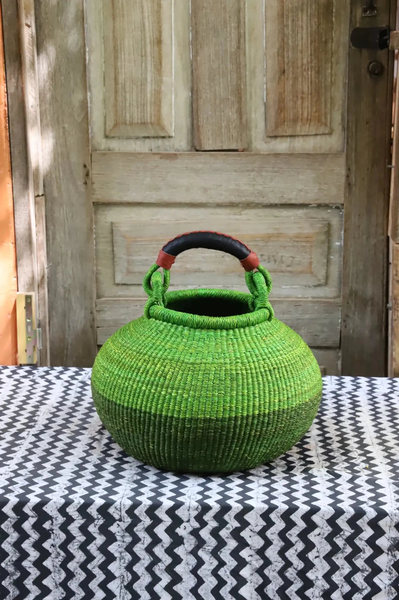 Colourful storage basket sitting on a black and white cloth against a wooden door.