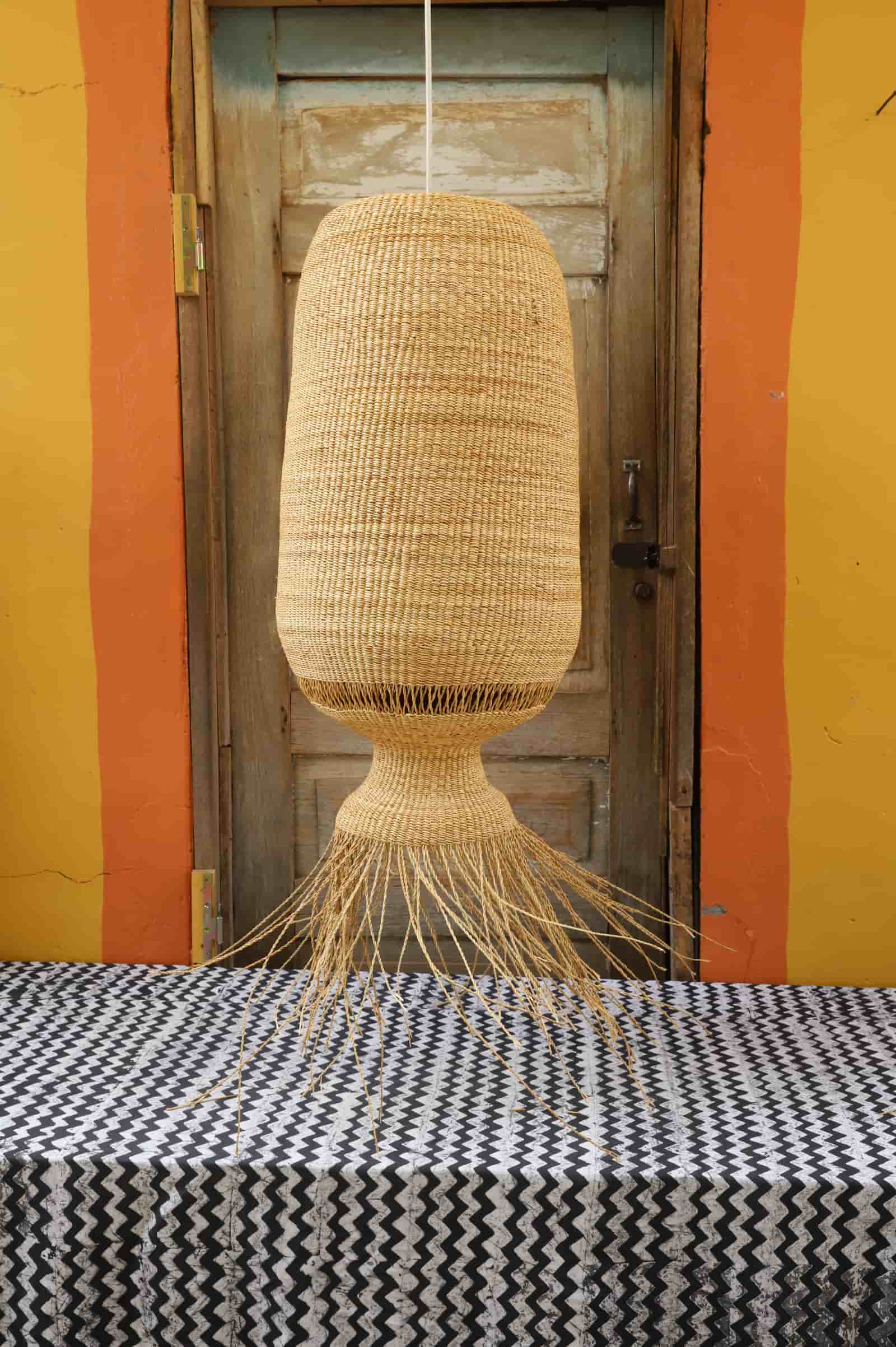 Woven lampshade on a table with a colorful wall and wooden door in the background