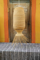 Woven basket hanging above a black and white patterned tablecloth with a striped wall in the background.