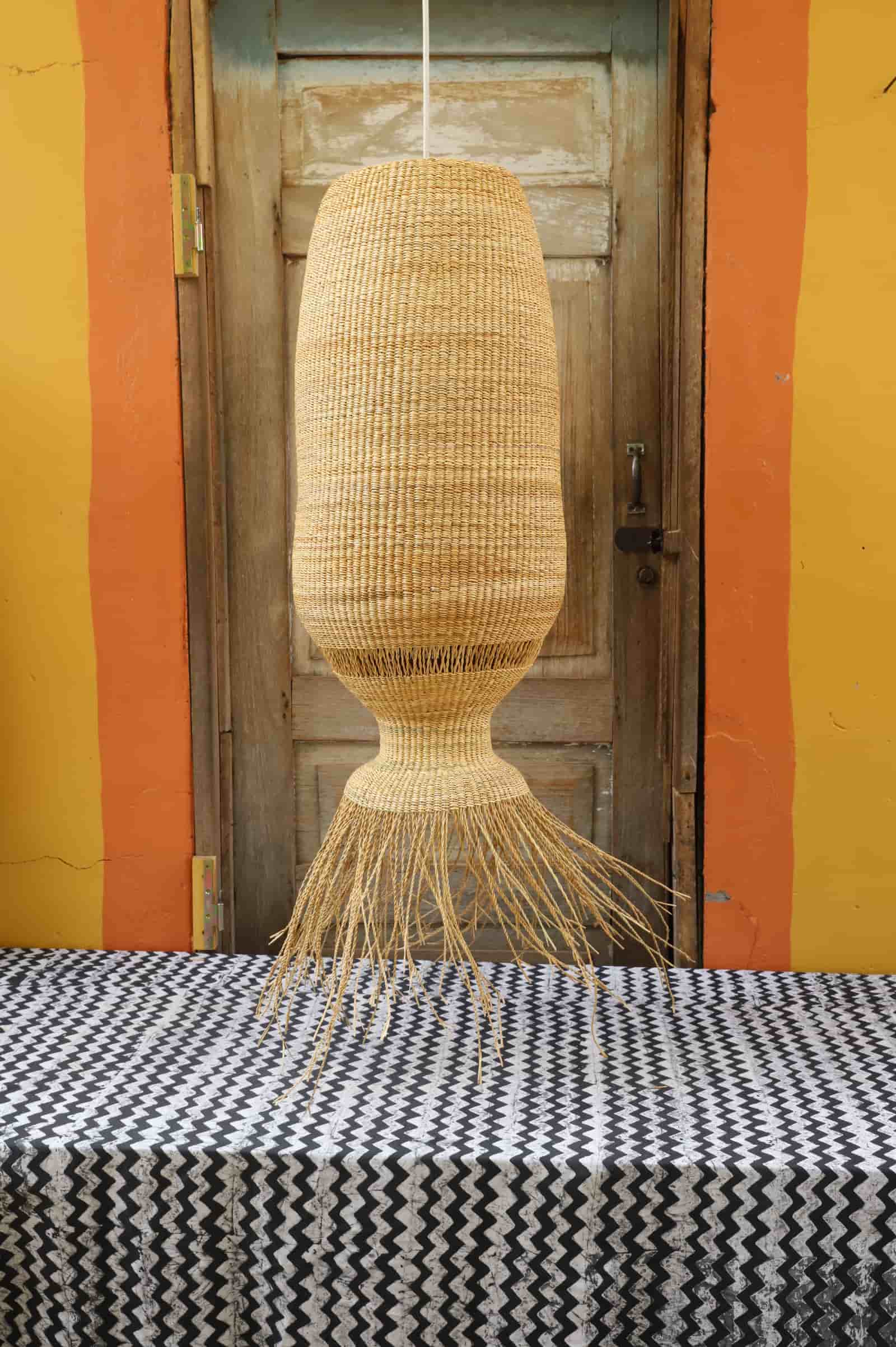 Woven basket hanging above a black and white patterned tablecloth with a striped wall in the background.