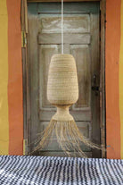 Woven pendant light hanging in front of a rustic wooden door with colorful walls.
