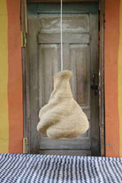 Woven basket hanging from a string in front of an open door with a colorful wall.