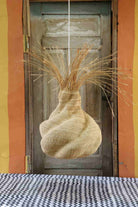 Decorative woven basket with straw-like material against a wooden door.