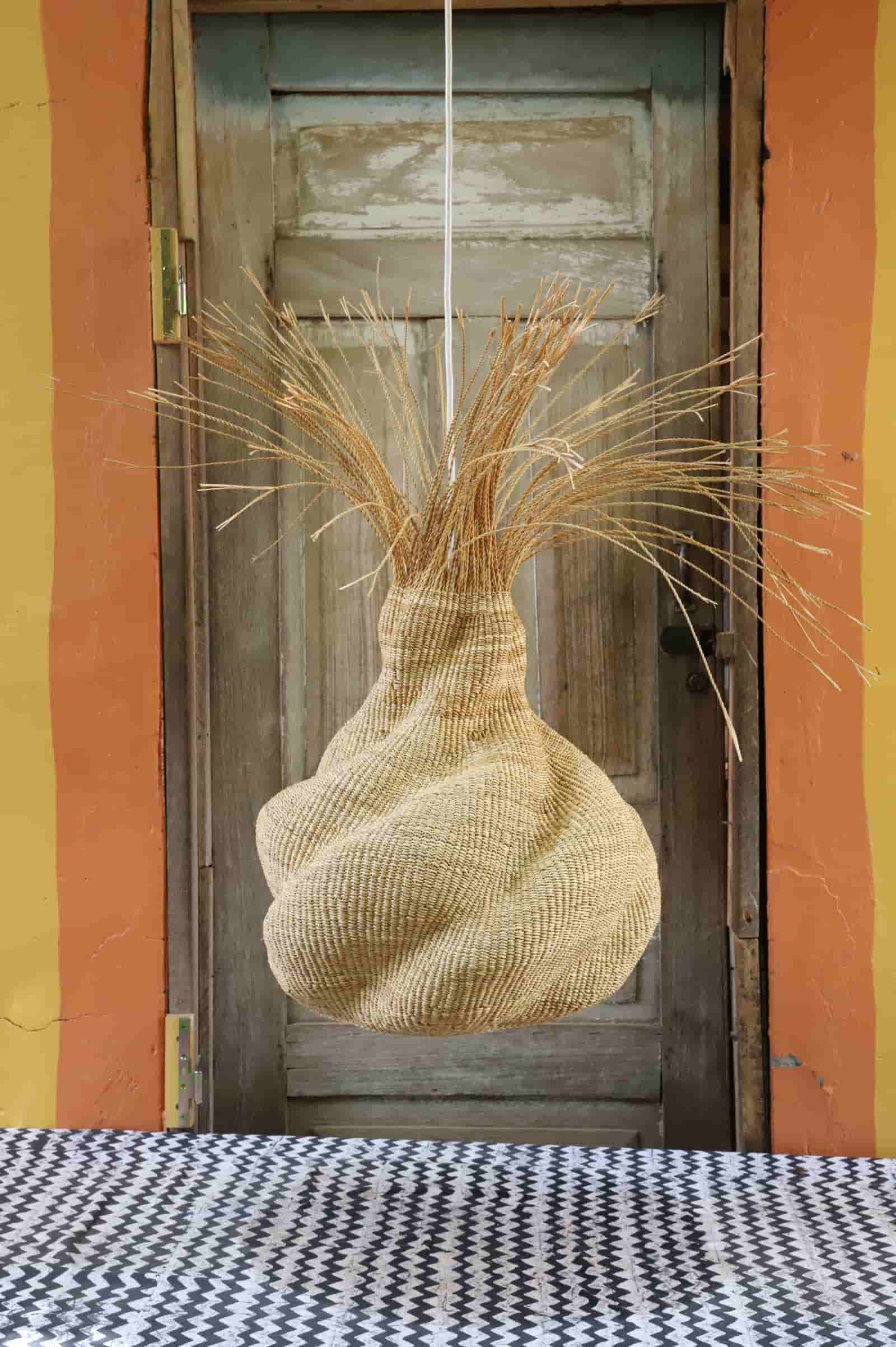 Decorative woven basket with straw-like material against a wooden door.
