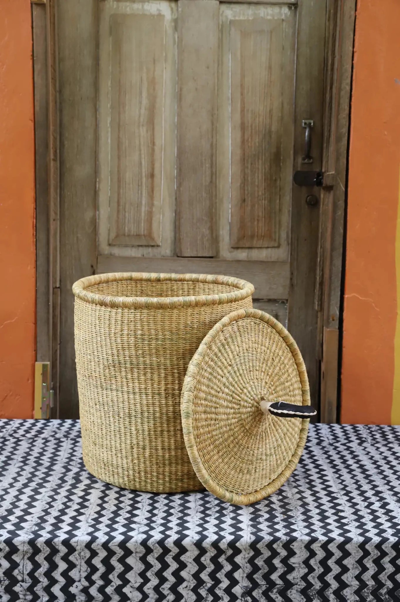 Lidded Laundry Basket with coil (Small) by The Baba Tree. Handwoven elephant grass with leather handle. Premium Bolgatanga artisan decor.