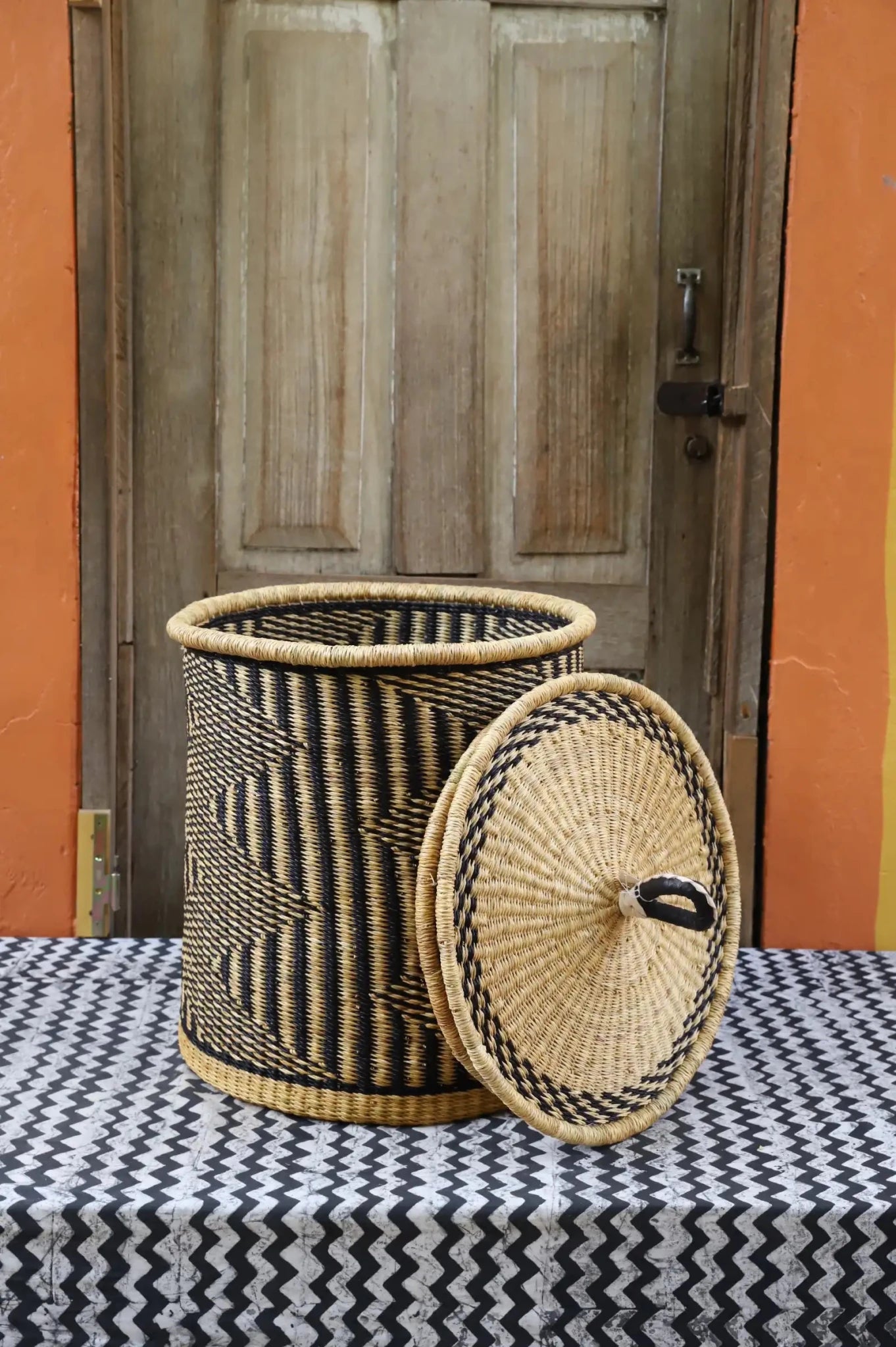 Lidded Laundry Basket with coil (Small) by The Baba Tree. Handwoven elephant grass with leather handle. Premium Bolgatanga artisan decor.