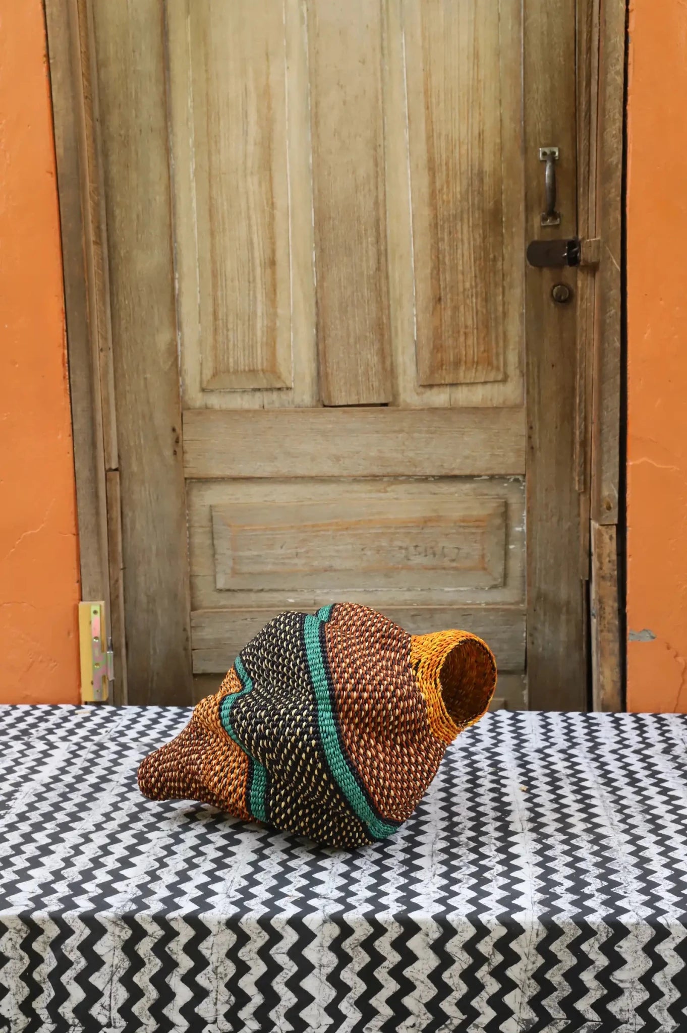 Colorful conch-shaped piece on a black and white cloth against a wooden door.