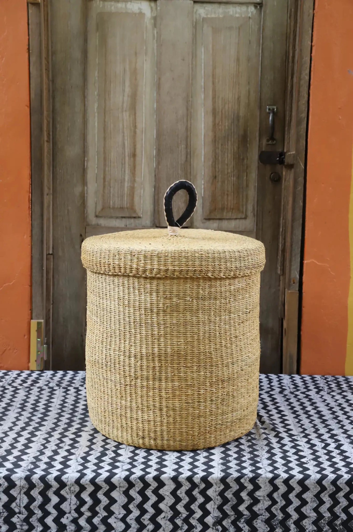 Lidded Laundry Basket (Medium) by The Baba Tree. Handwoven elephant grass with leather handle. Premium Bolgatanga artisan decor.