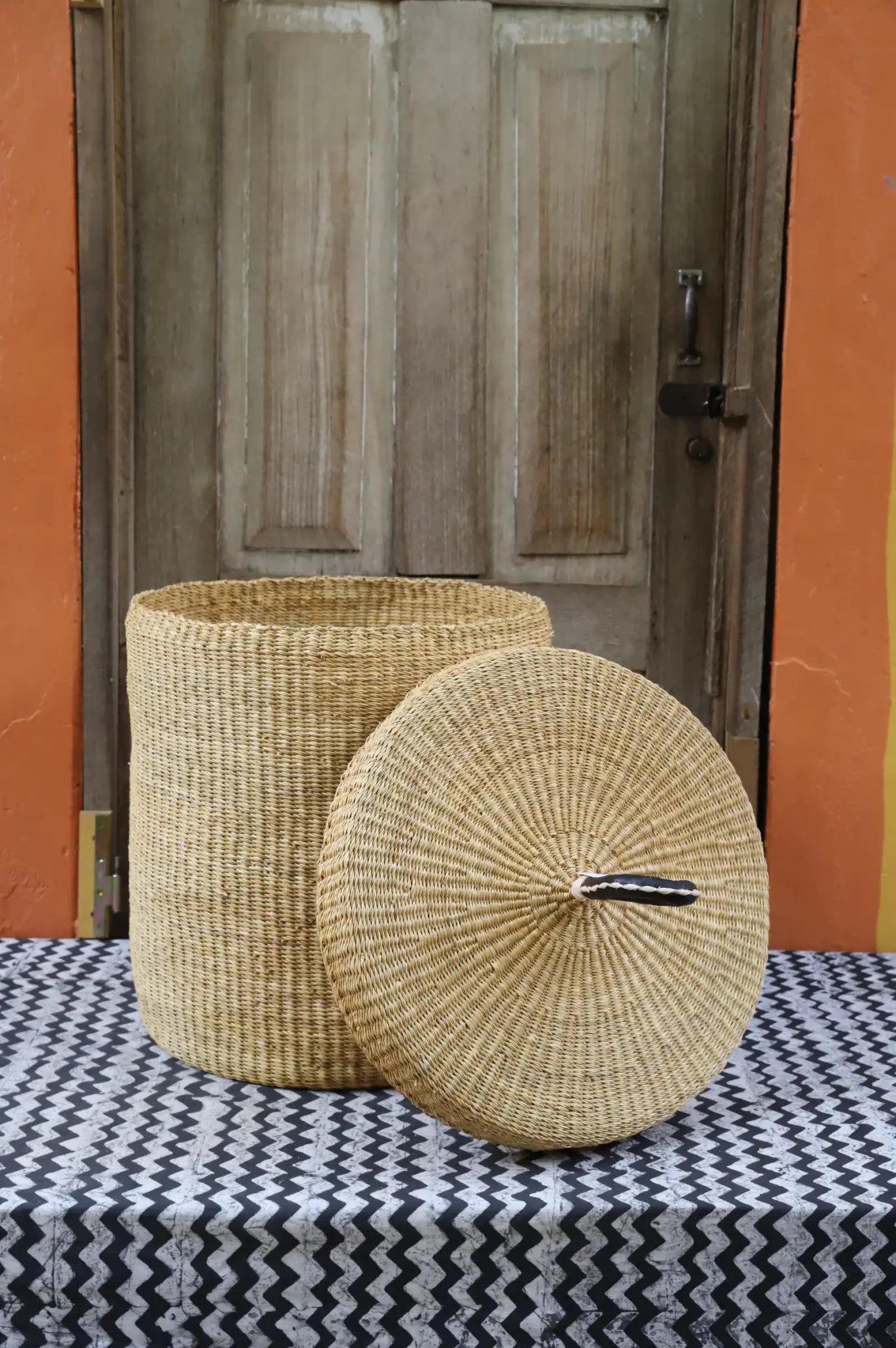 Lidded Laundry Basket (Medium) by The Baba Tree. Handwoven elephant grass with leather handle. Premium Bolgatanga artisan decor.