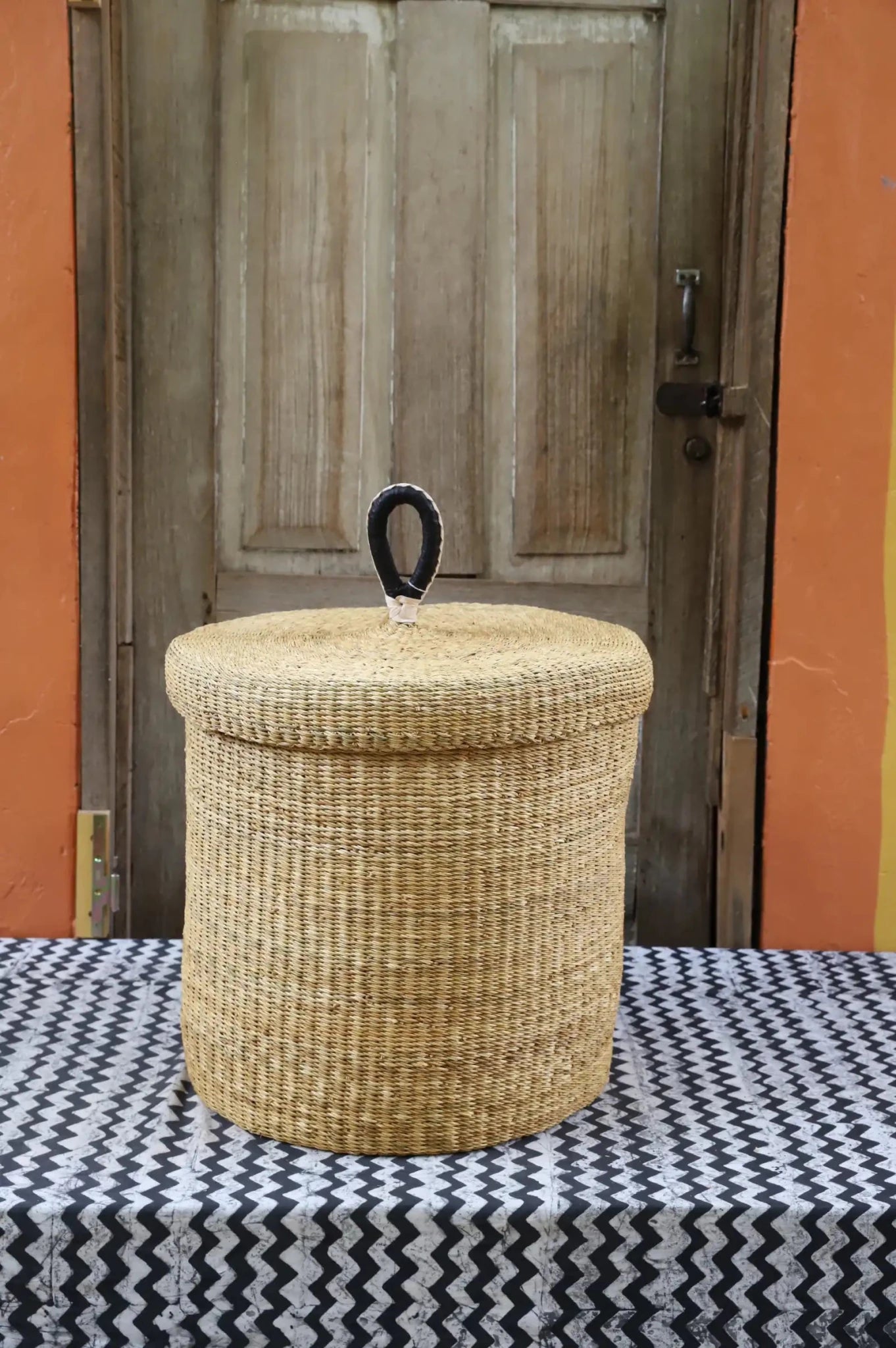 Lidded Laundry Basket (Medium) by The Baba Tree. Handwoven elephant grass with leather handle. Premium Bolgatanga artisan decor.