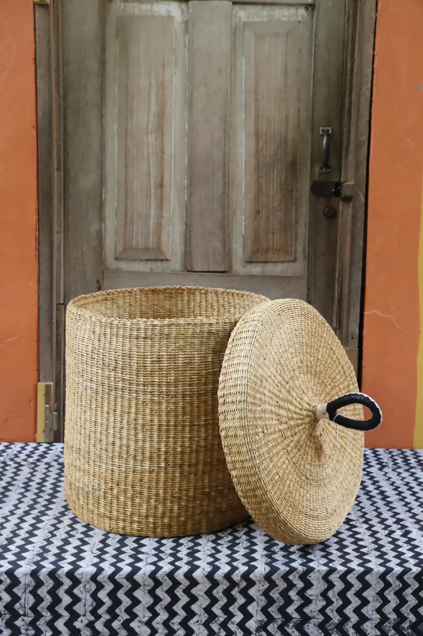 Lidded Laundry Basket (Medium) by The Baba Tree. Handwoven elephant grass with leather handle. Premium Bolgatanga artisan decor.