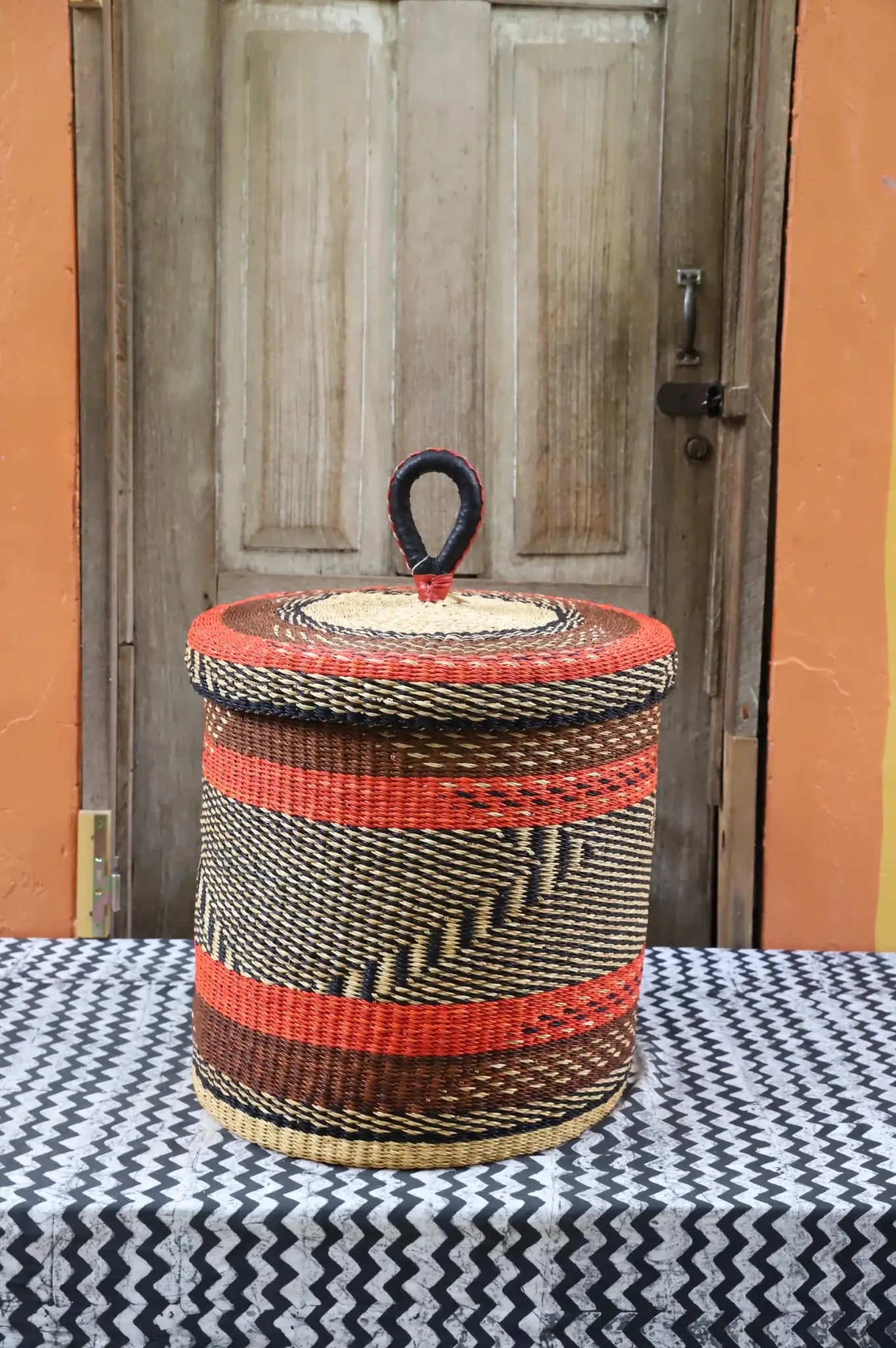 Lidded Laundry Basket (Medium) by The Baba Tree. Handwoven elephant grass with leather handle. Premium Bolgatanga artisan decor.