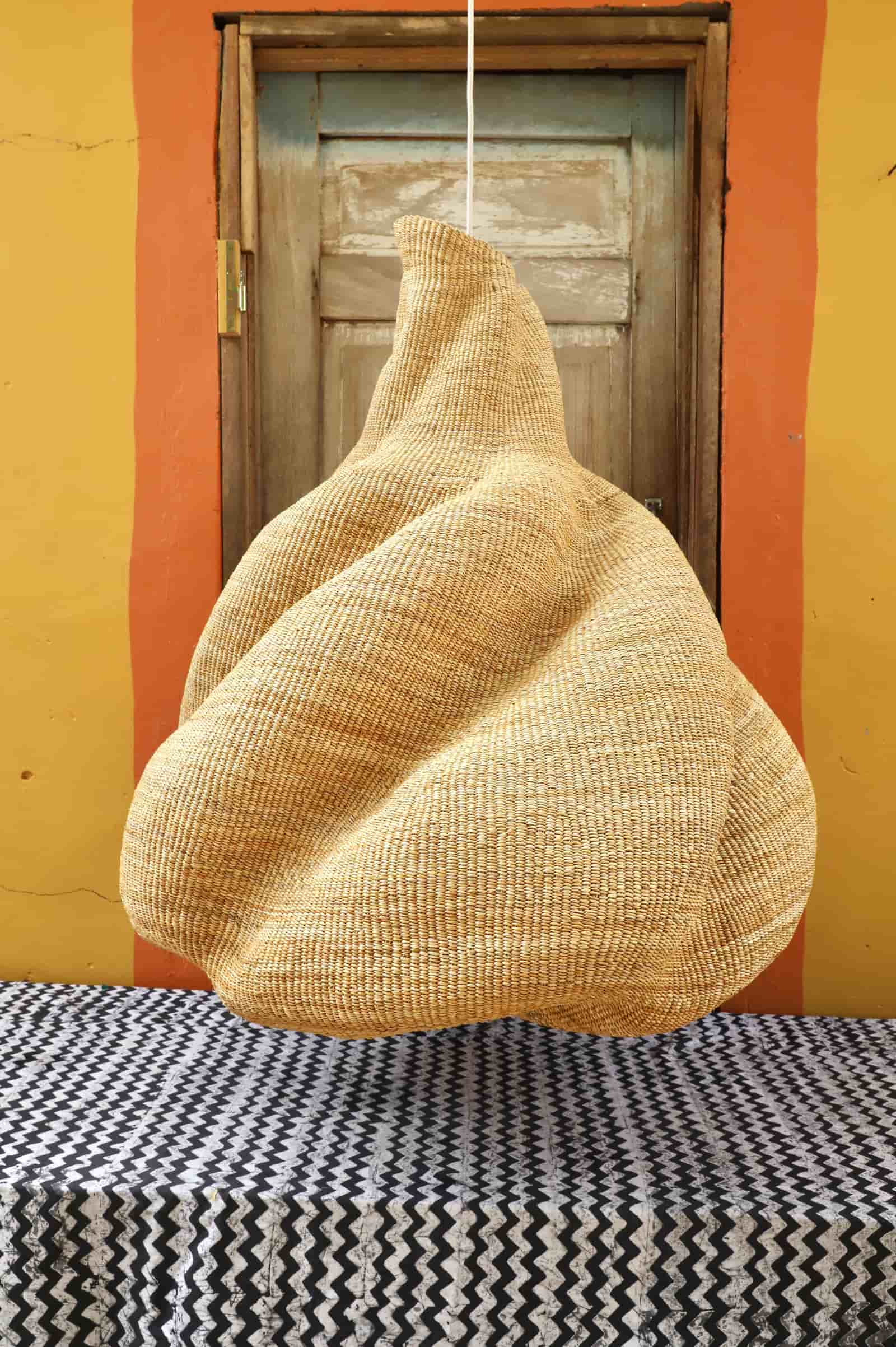 Woven basket hanging against a yellow wall with a wooden door.