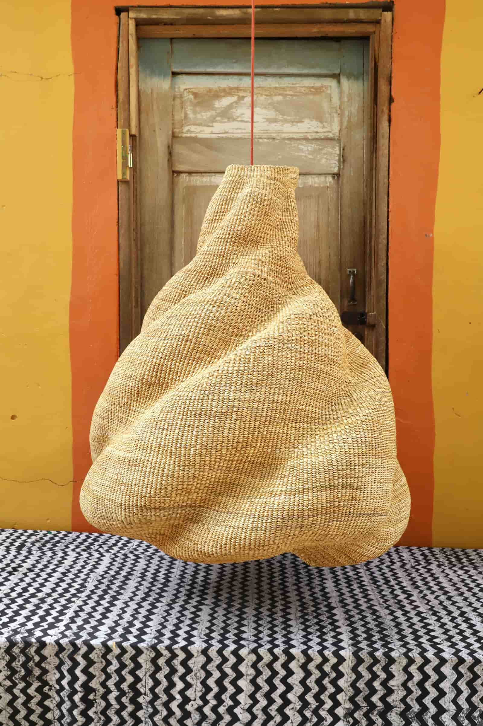 Woven basket hanging against a colorful wall with a door in the background