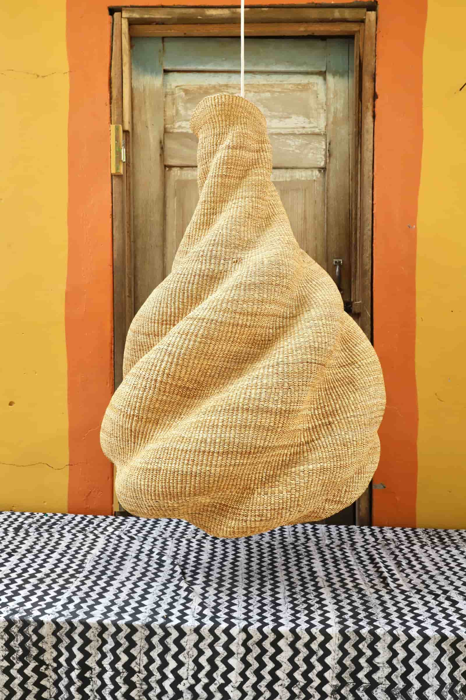 Textured woven on a black and white patterned surface with a yellow wall and wooden door in the background.