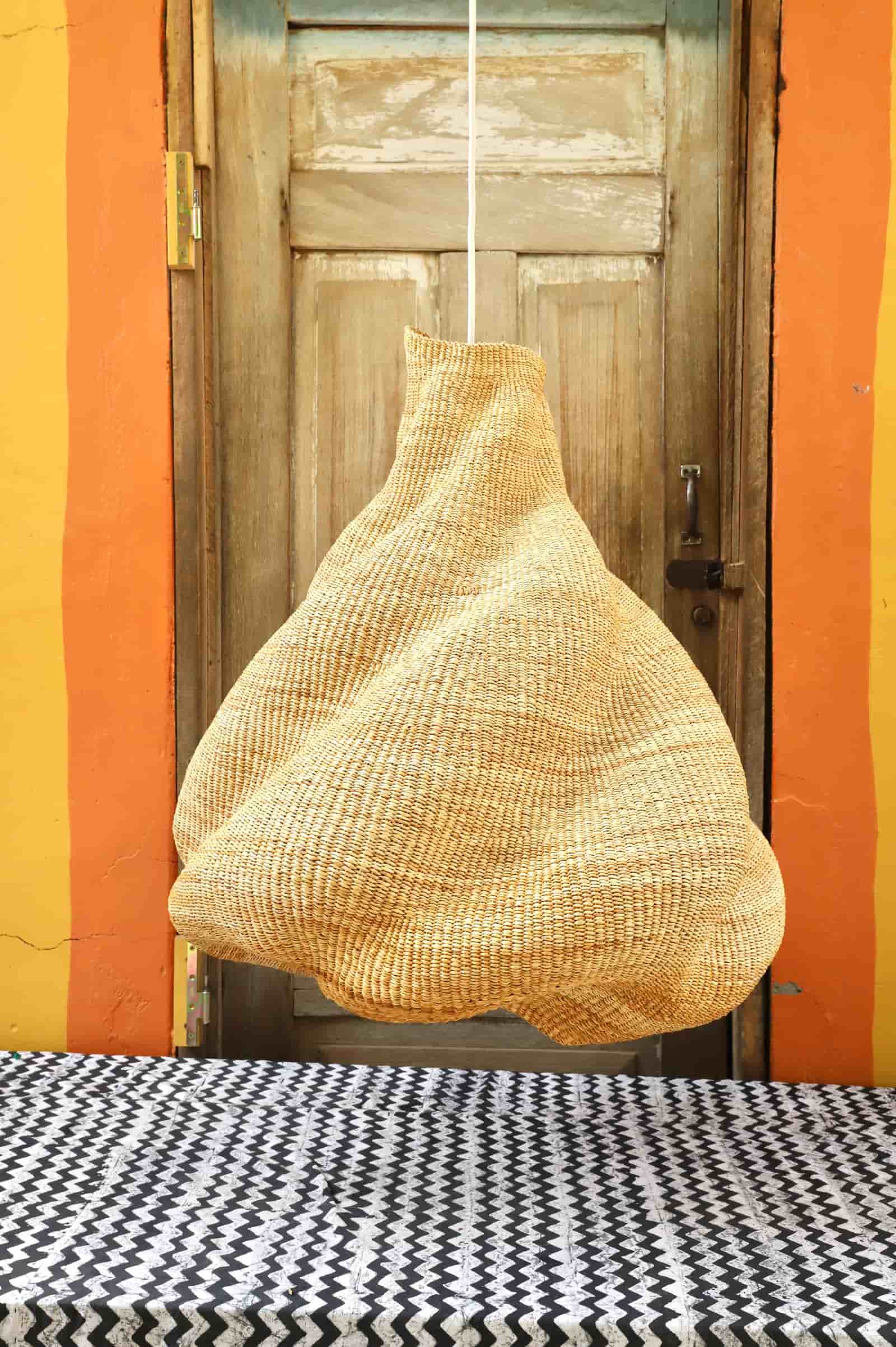 Woven basket hanging on a wooden door with an orange wall in the background