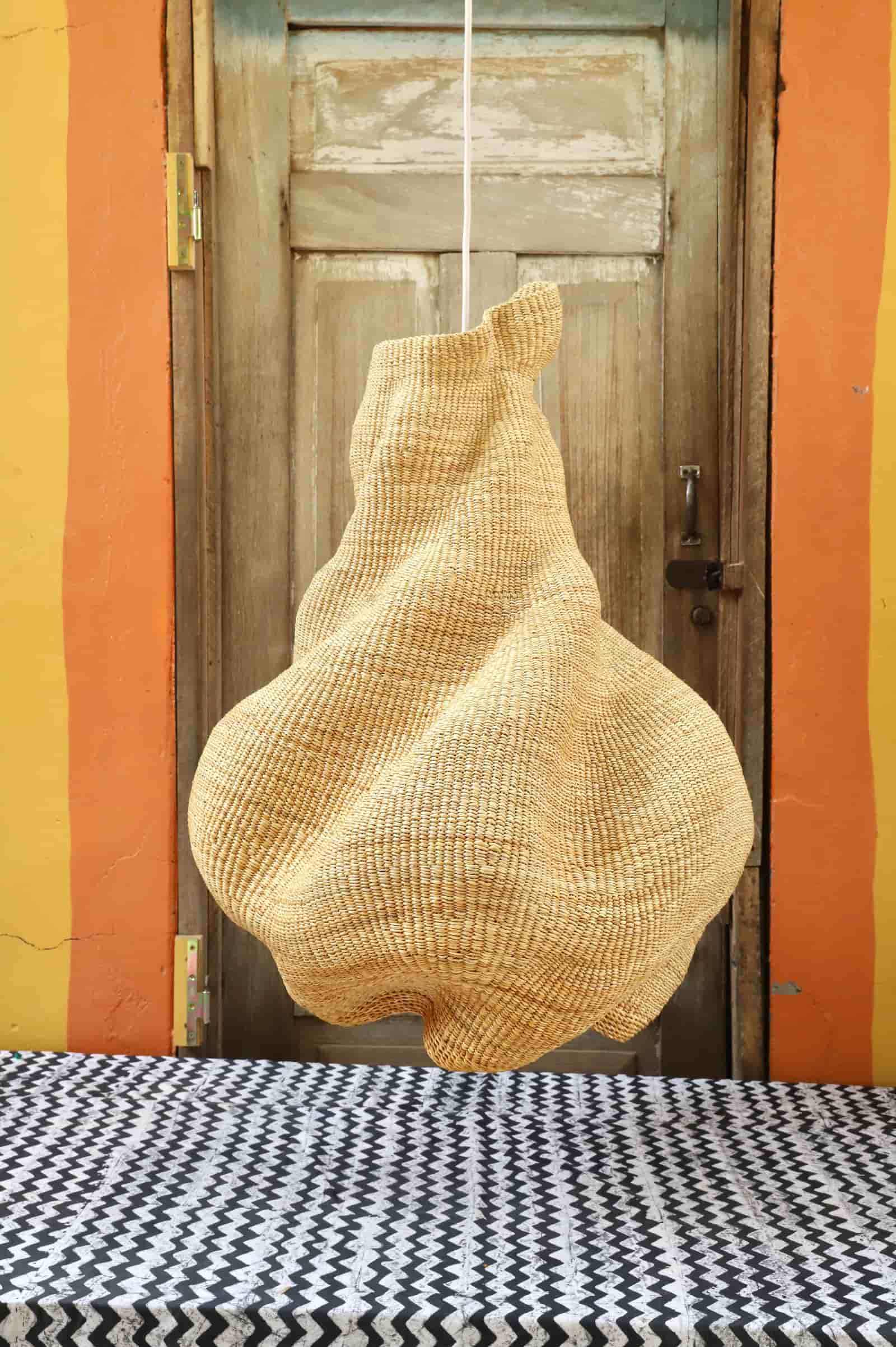 Woven basket hanging on a wooden door with a colorful wall and patterned floor.