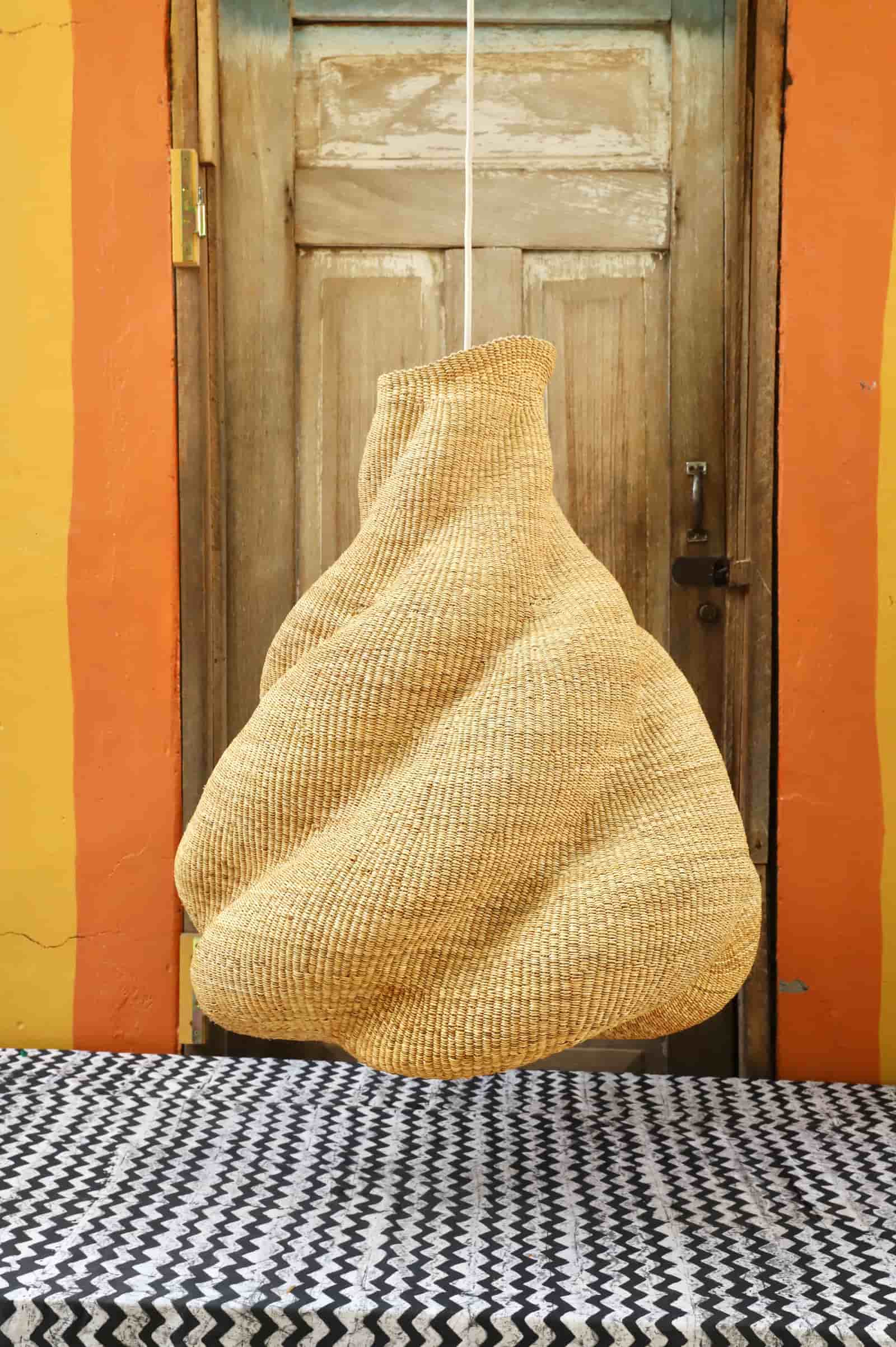 Woven basket hanging against a wooden door with orange walls.