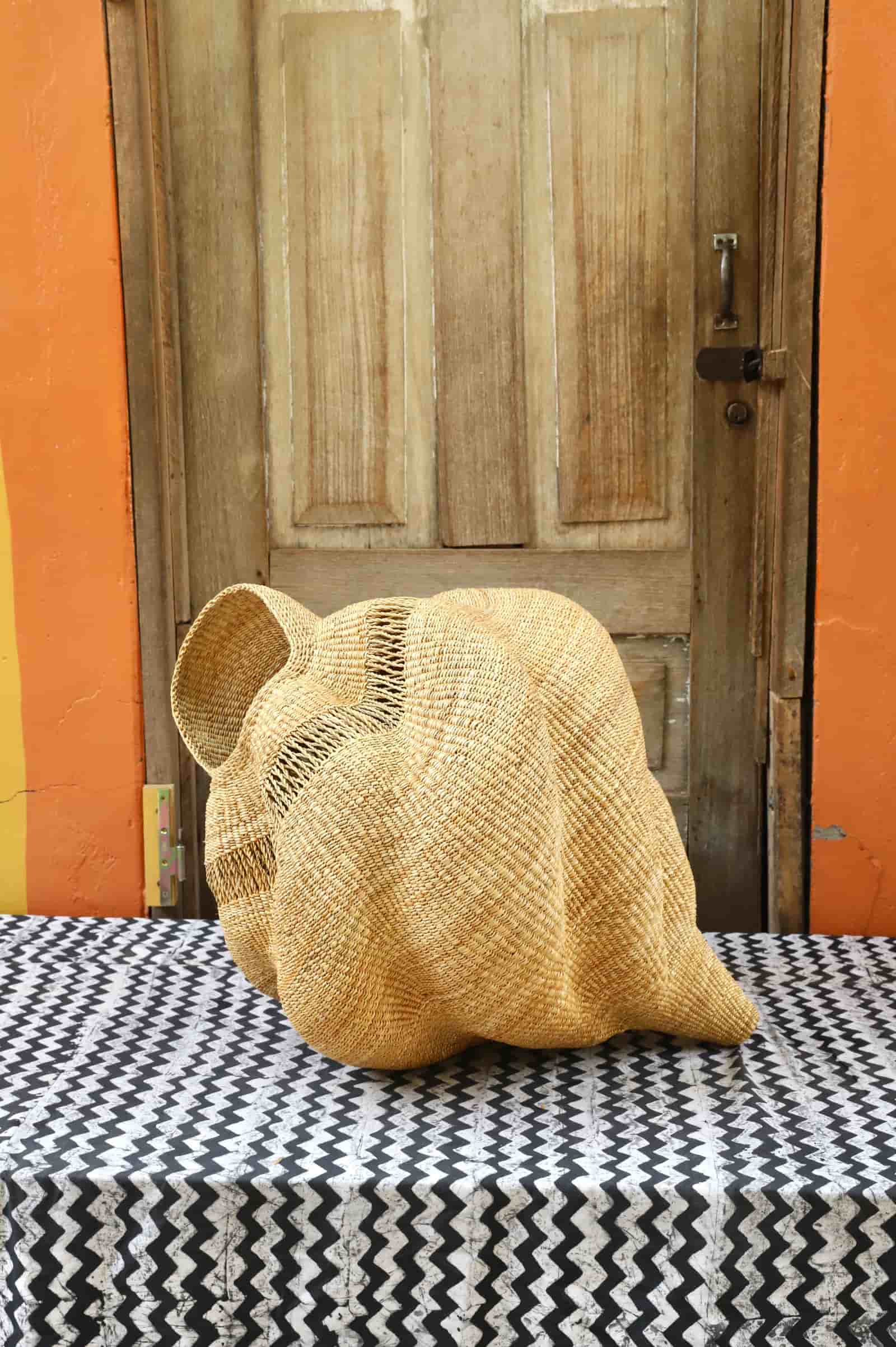 Conch-shaped lampshade on a black and white cloth against a wooden door.