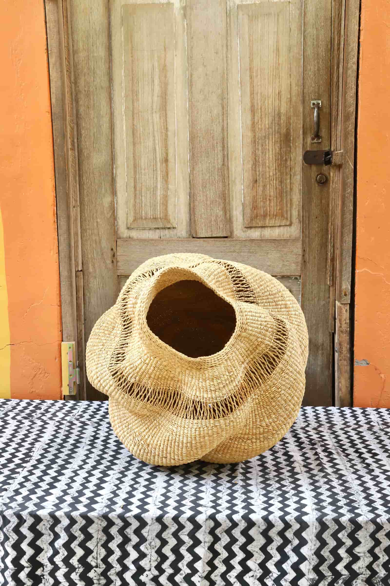 Woven conch on a table with a wooden door and orange wall in the background