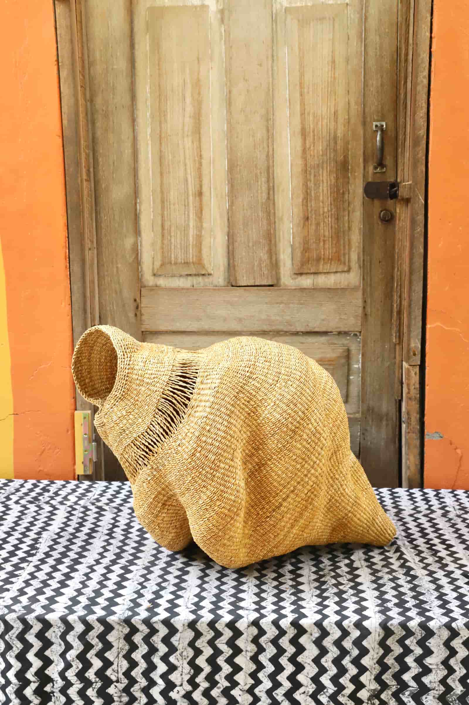 Conch-shaped lampshade on a black and white cloth against a wooden door.