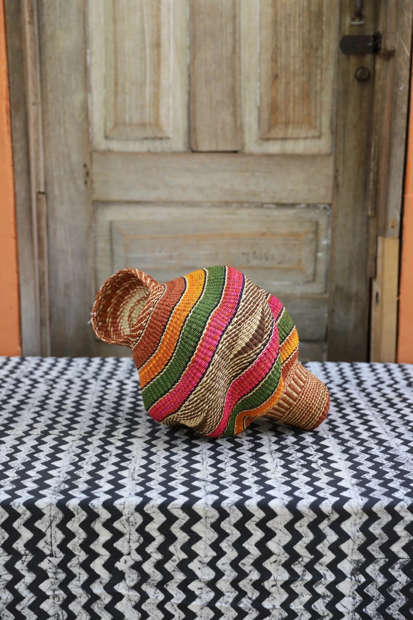 Colorful conch-shaped piece on a black and white cloth against a wooden door.