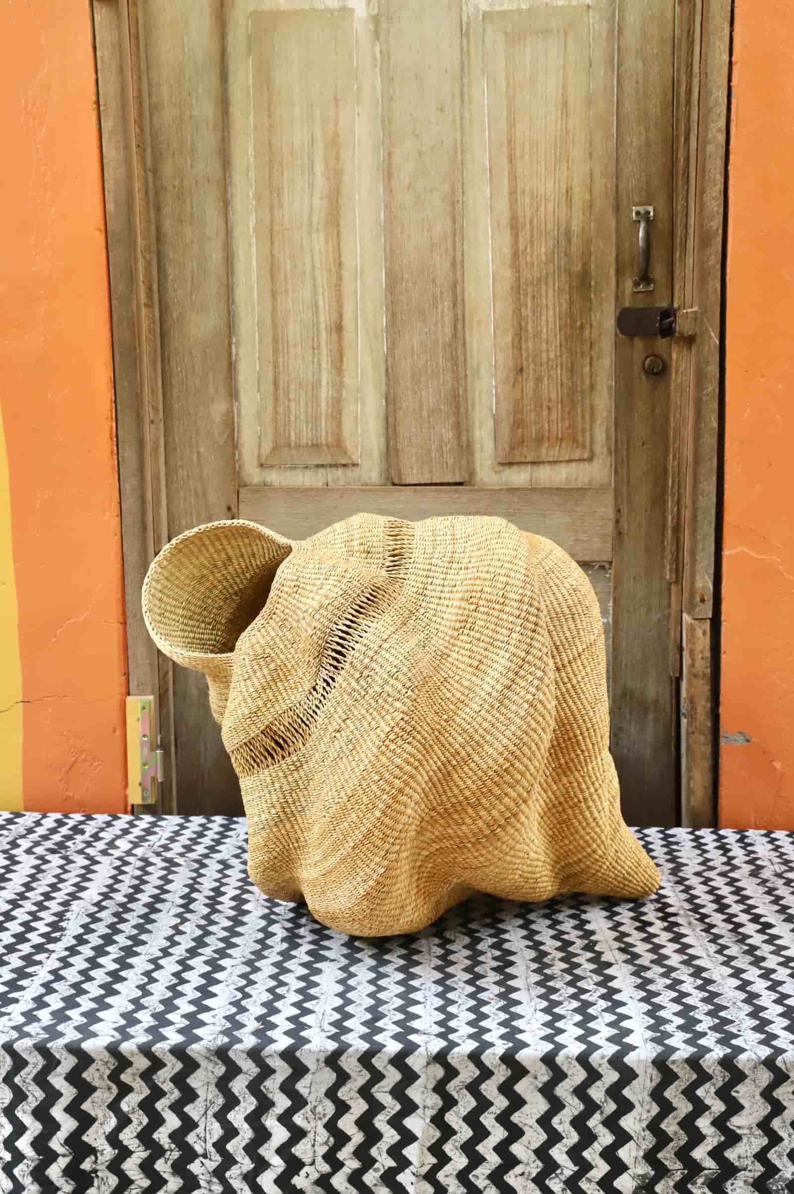 Conch-shaped lampshade on a black and white cloth against a wooden door.