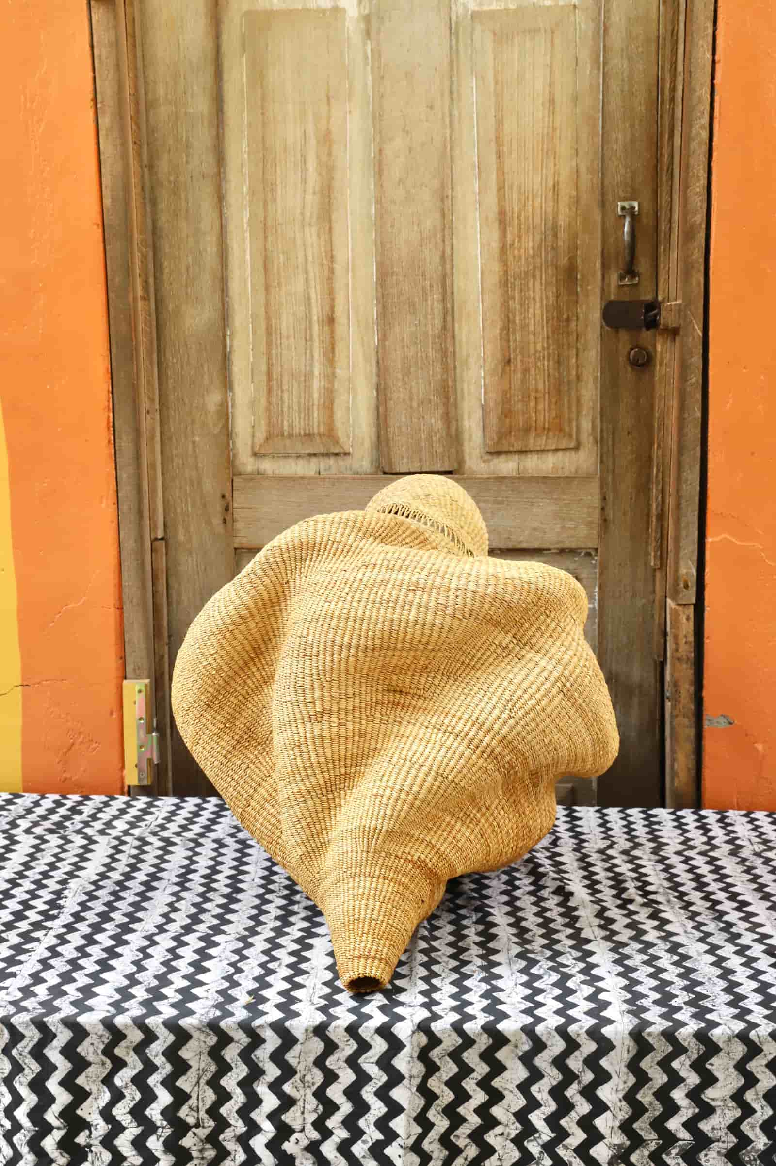 Conch-shaped lampshade on a black and white cloth against a wooden door.