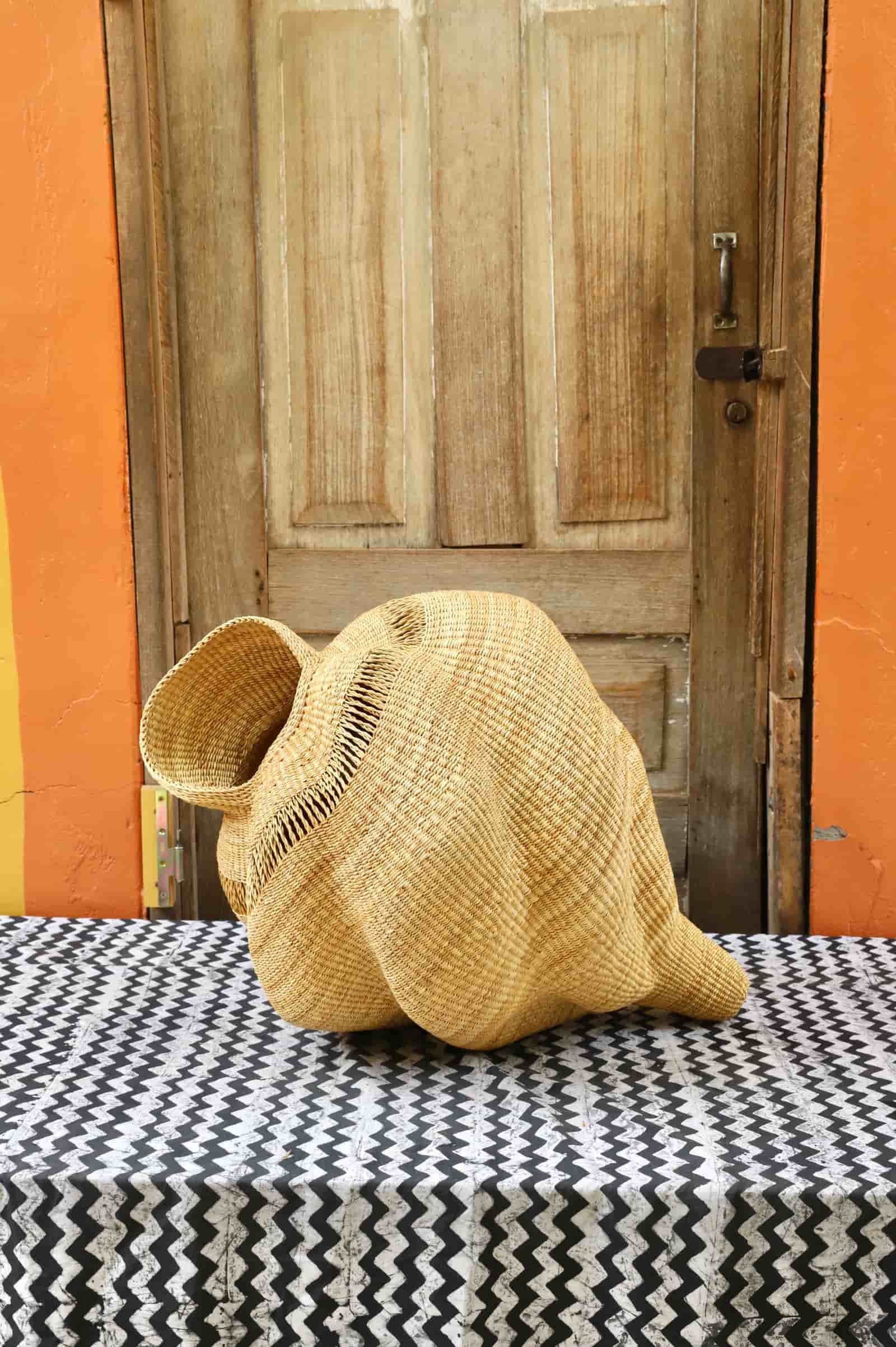 Conch-shaped lampshade on a black and white cloth against a wooden door.