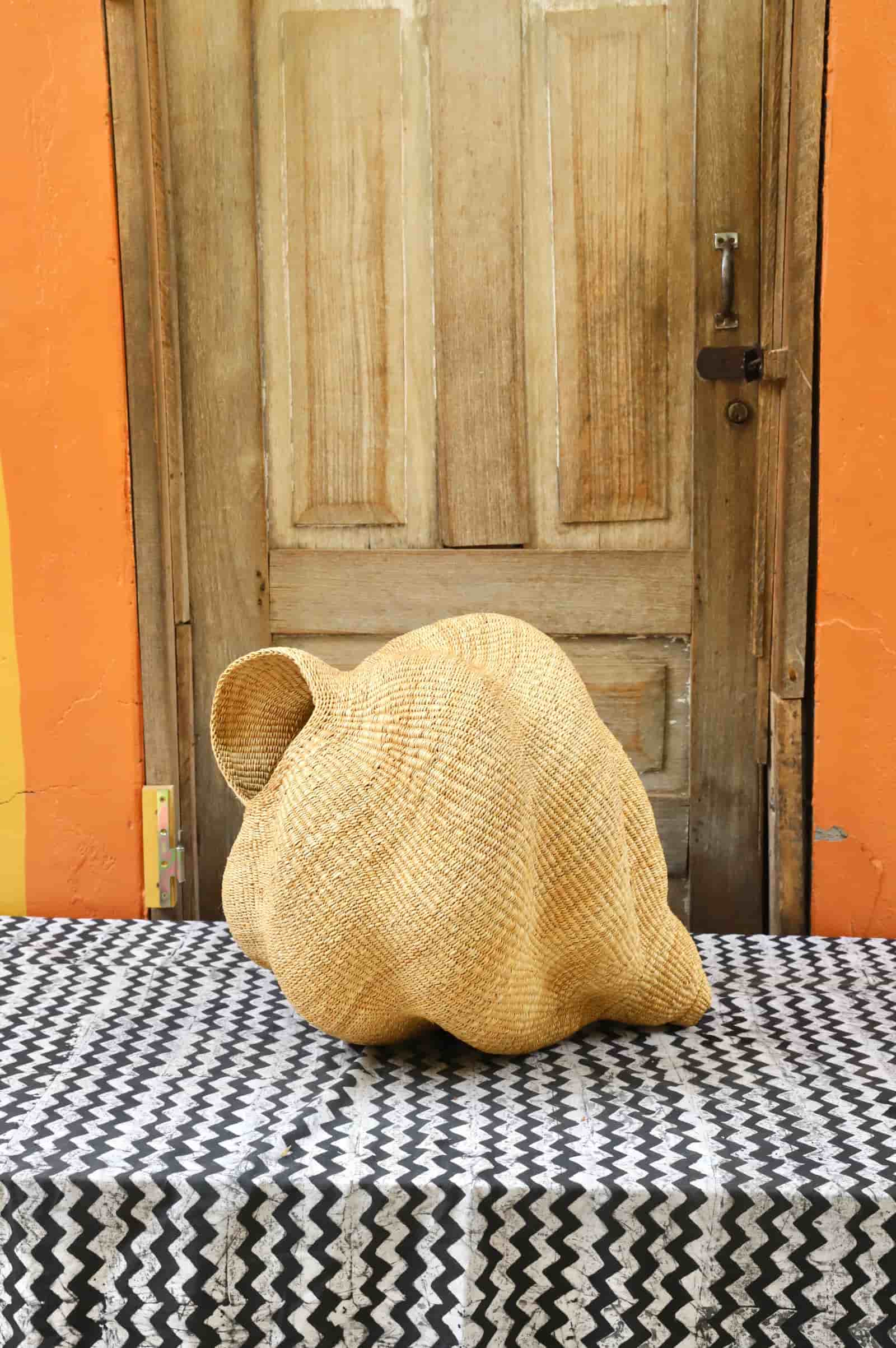 Conch-shaped lampshade on a black and white cloth against a wooden door.