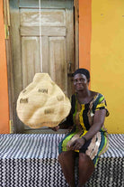 Woman holding a woven basket in front of a colorful wall.