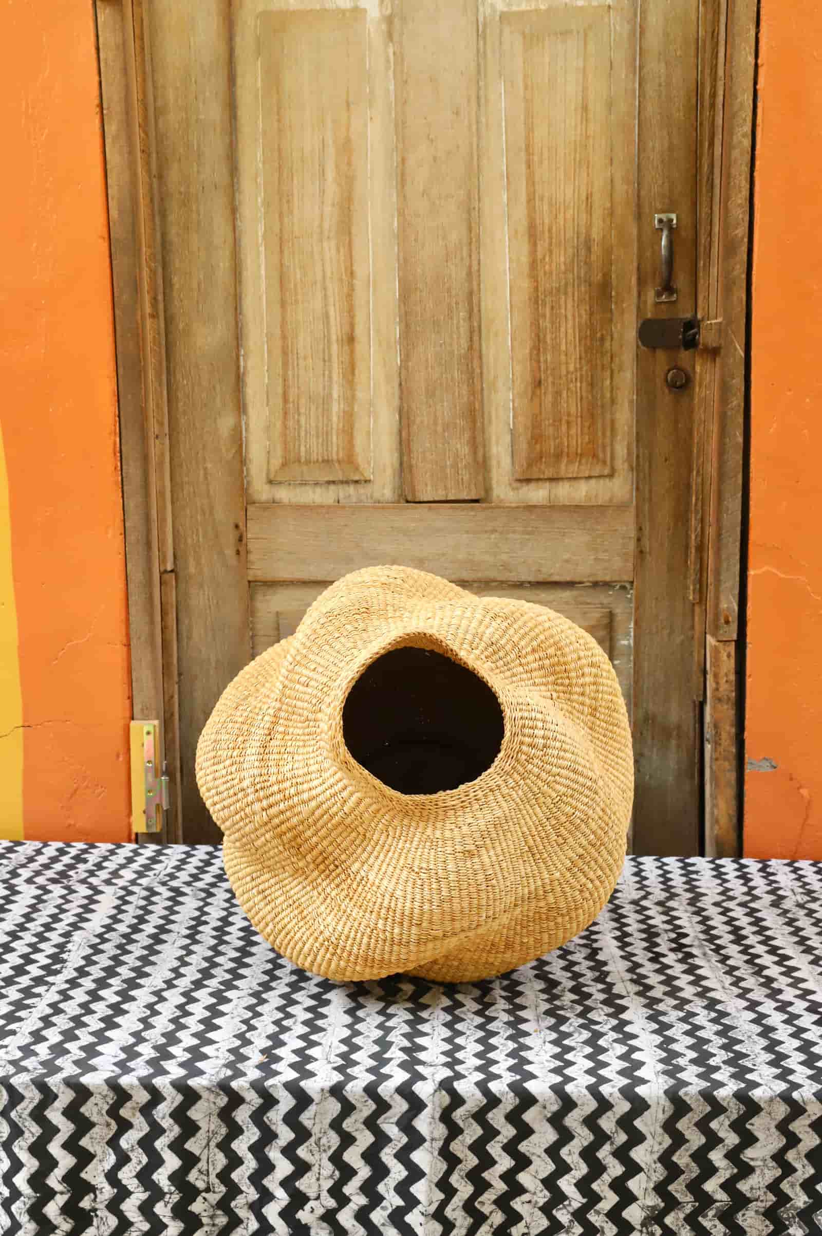 Conch-shaped lampshade on a black and white cloth against a wooden door.