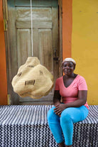 Woman sitting on a bench with a colorful background and woven basket.