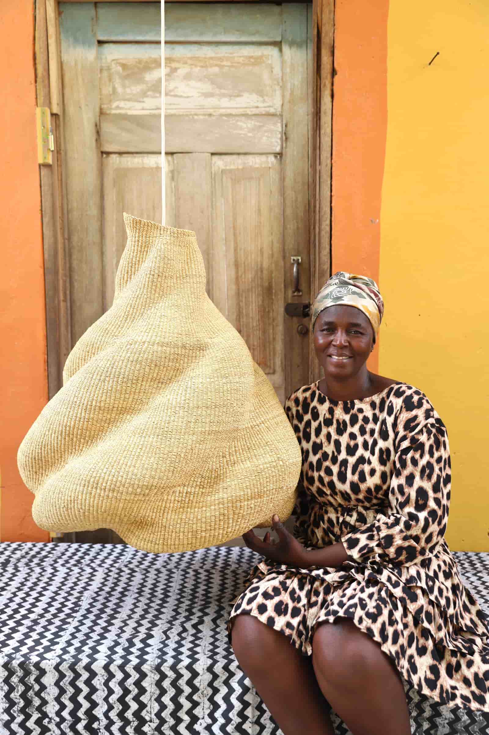 Woman in leopard print dress holding a woven basket against a colorful wall.