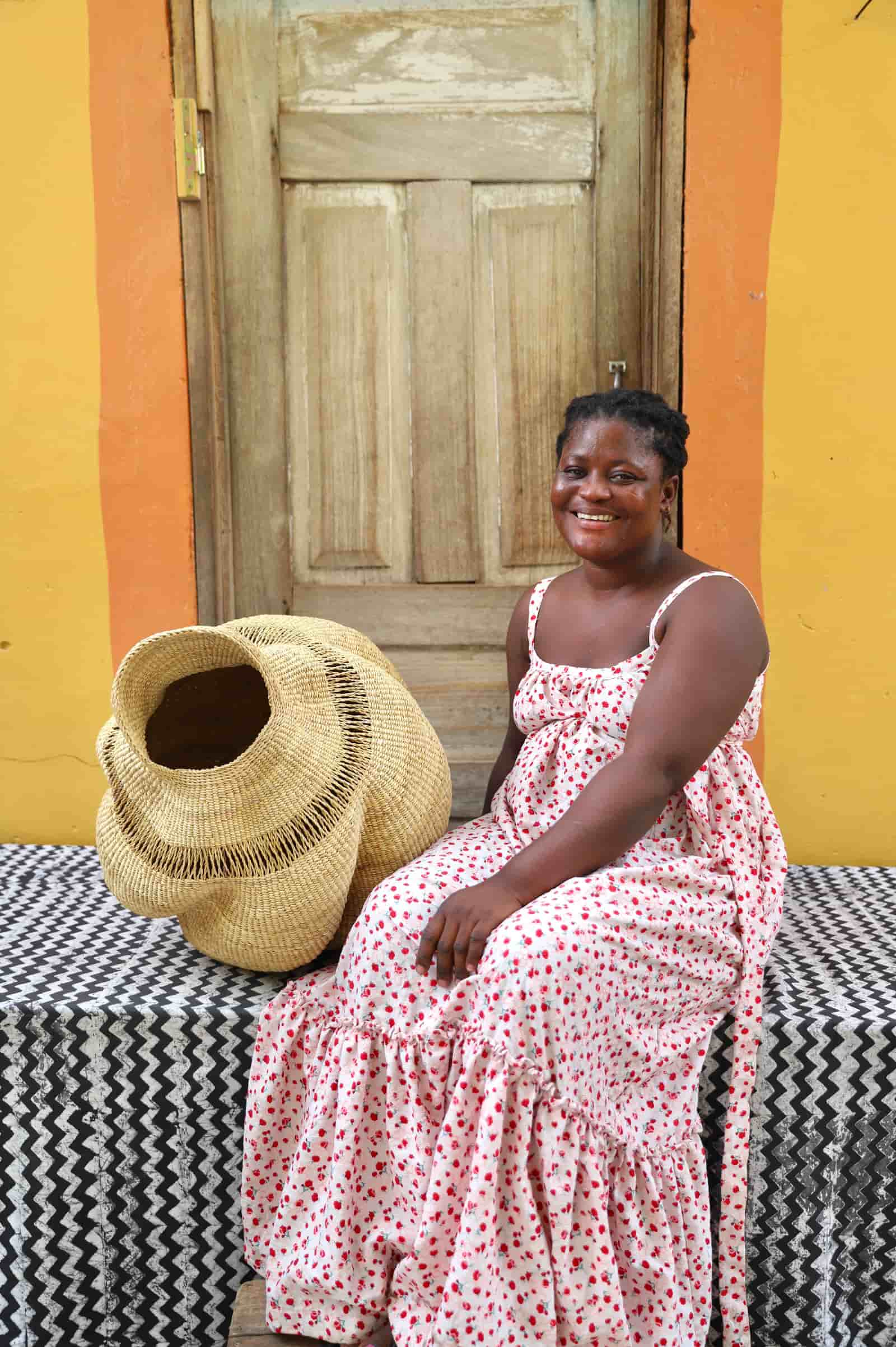 Woven conch-shaped lampshade on a black and white patterned cloth with a wooden door in the background.