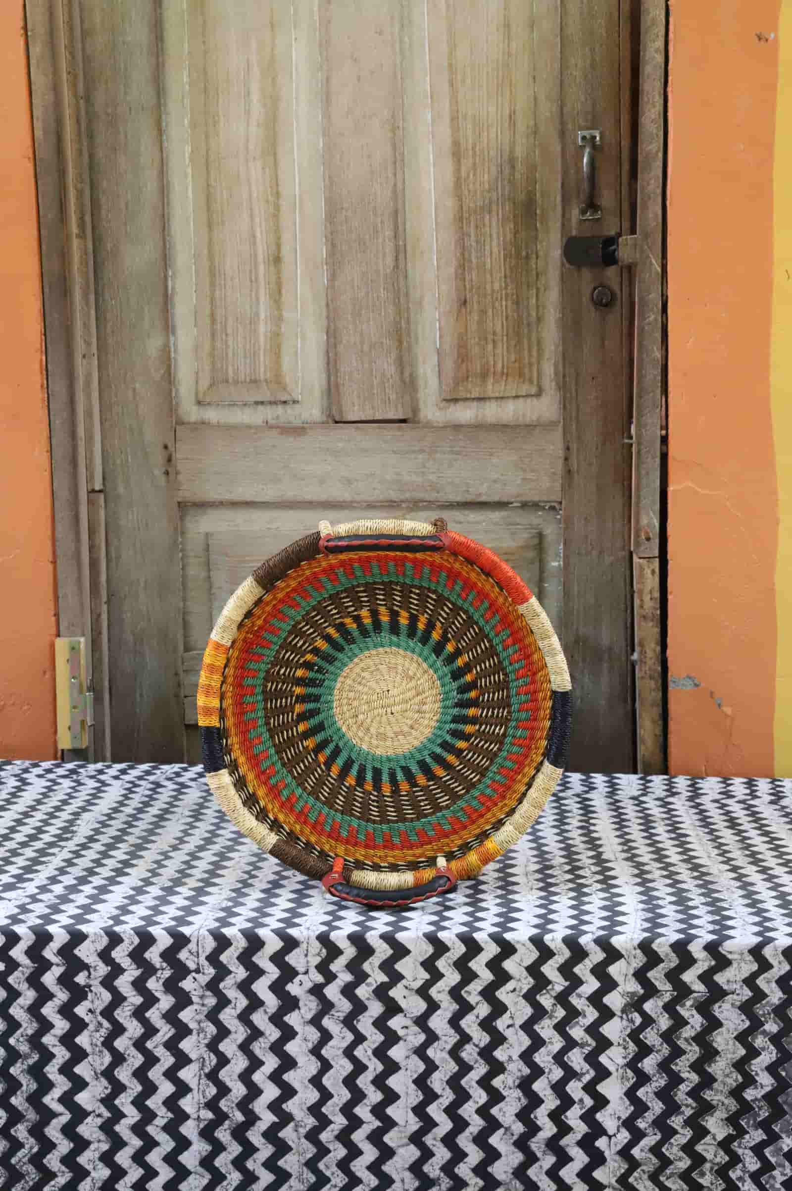 Decorative woven basket on a table with a wooden door in the background