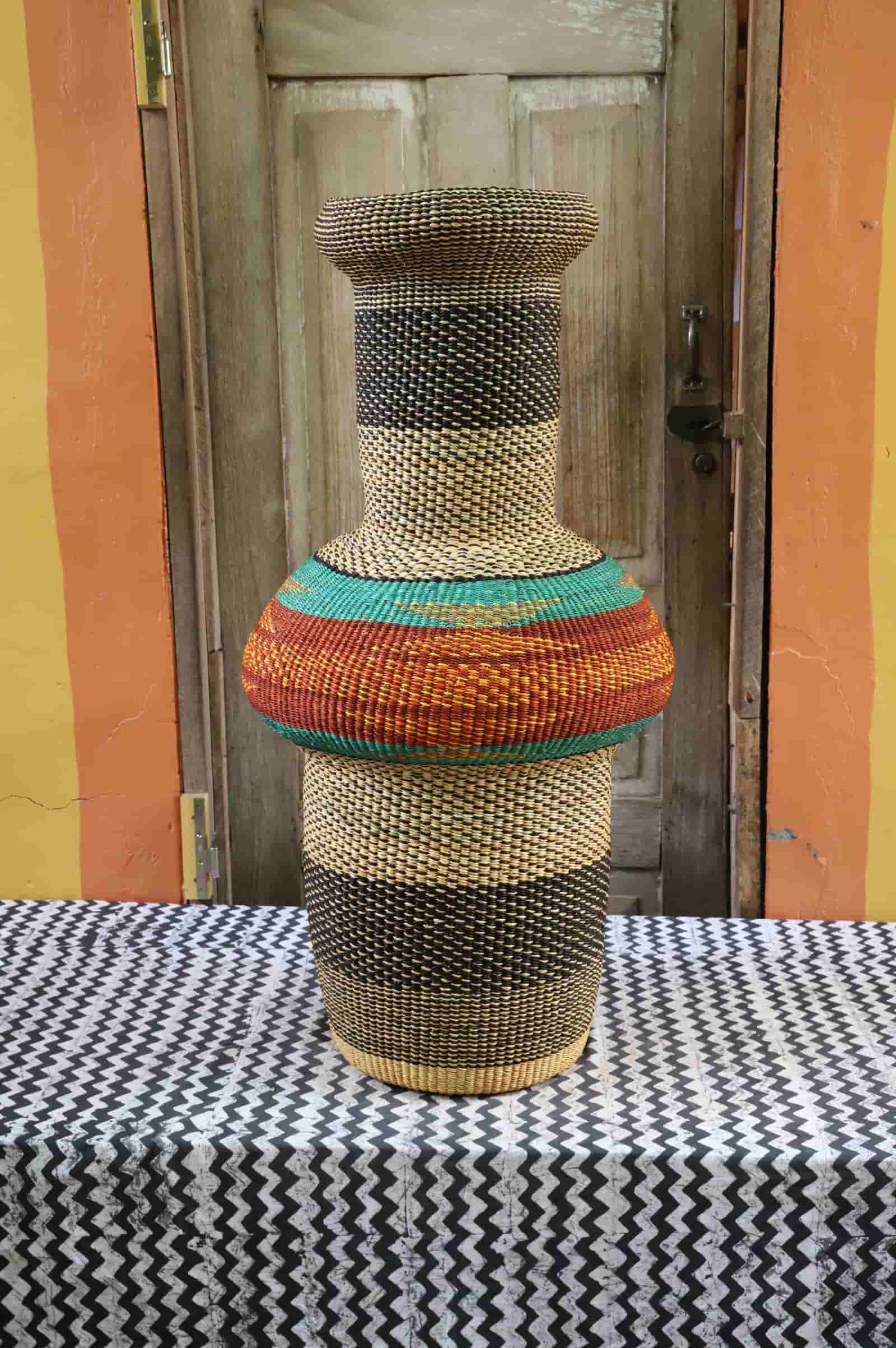 Colorful, woven décor piece on a black and white cloth against a wooden door.