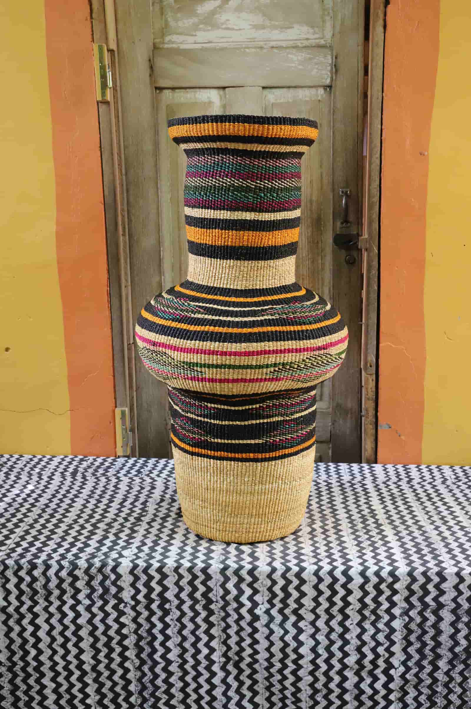 Colorful, woven décor piece on a black and white cloth against a wooden door.