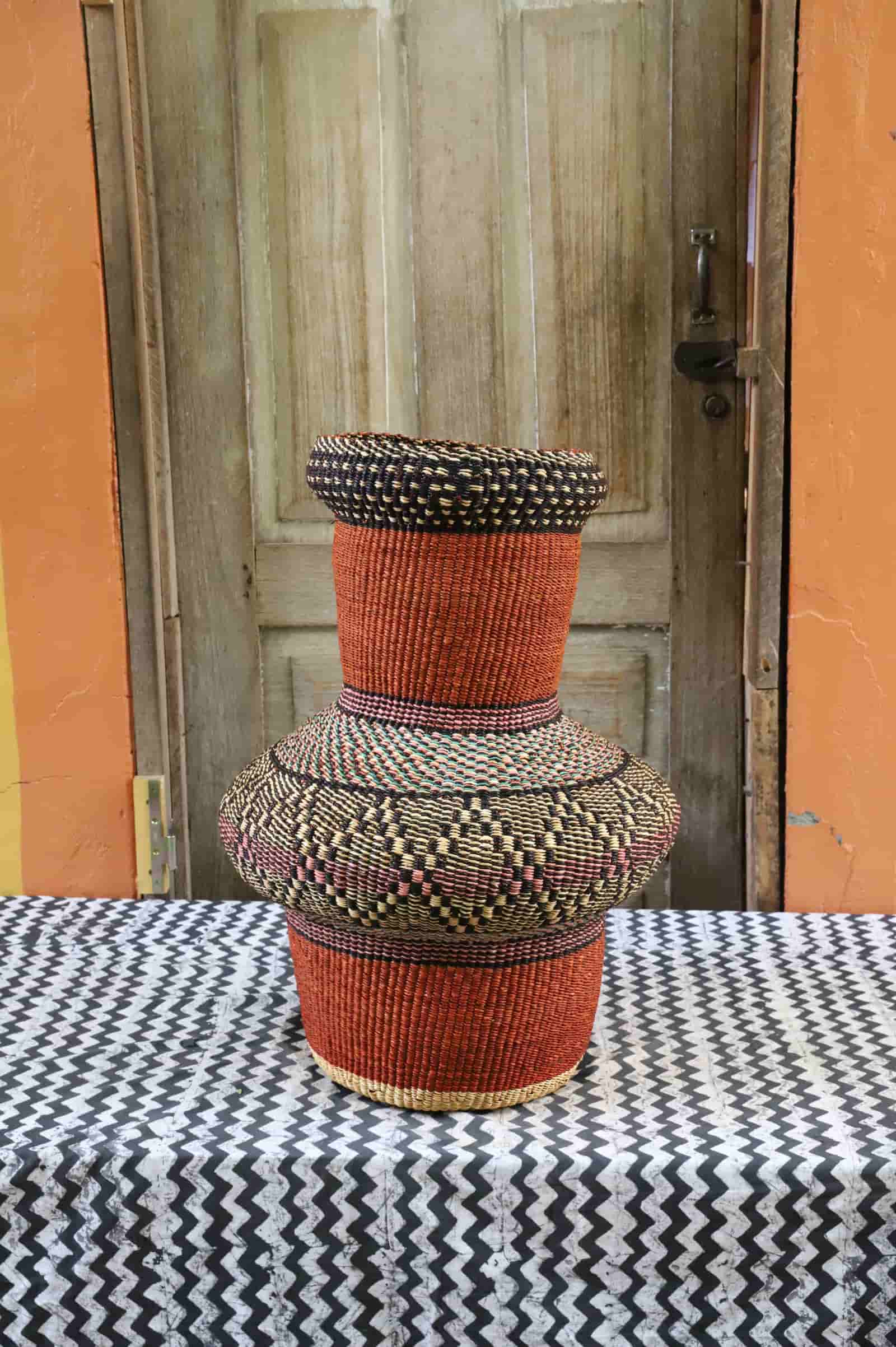 Colorful, woven décor piece on a black and white cloth against a wooden door