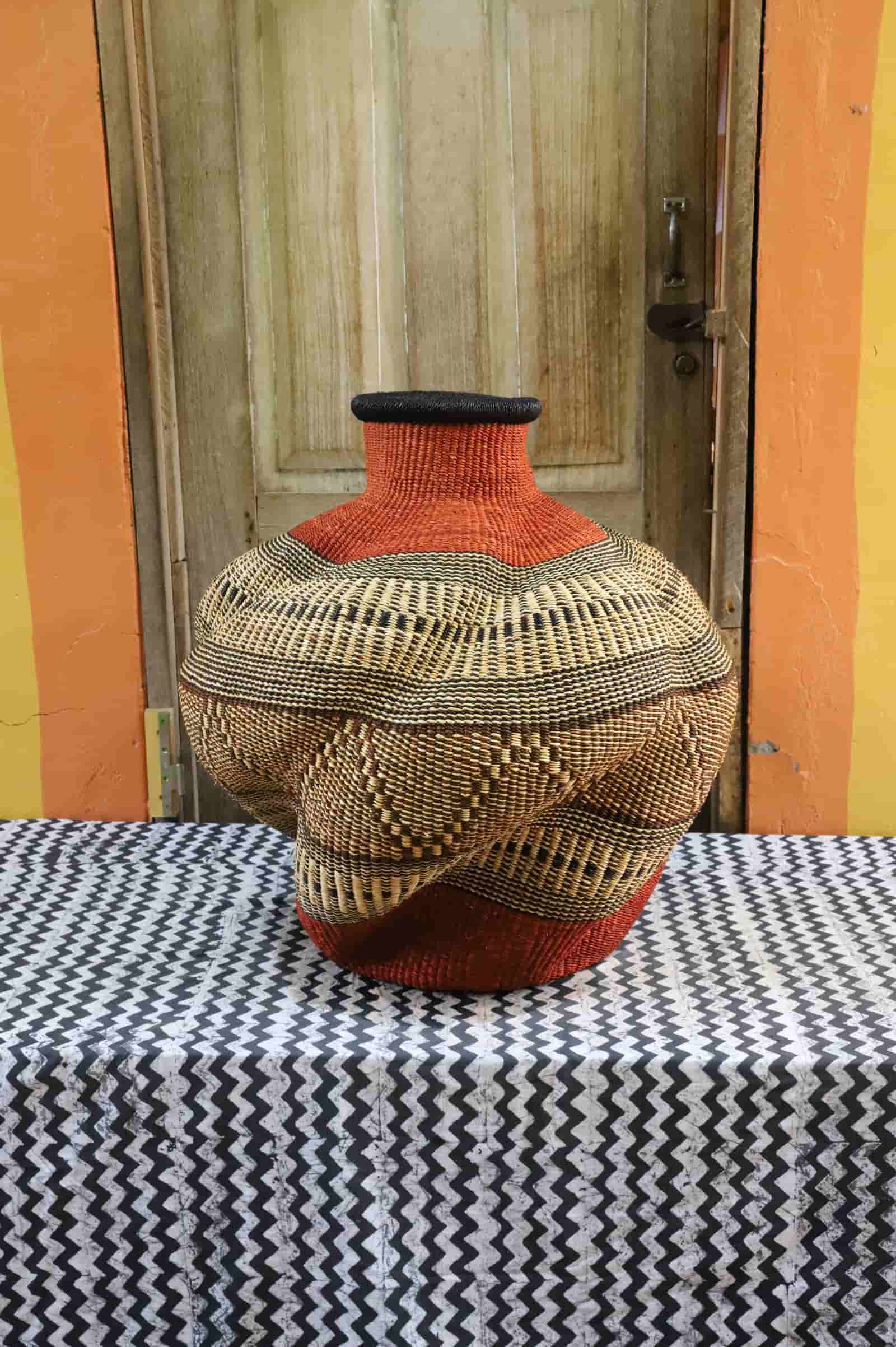 Large, colorful woven basket against a yellow wall.