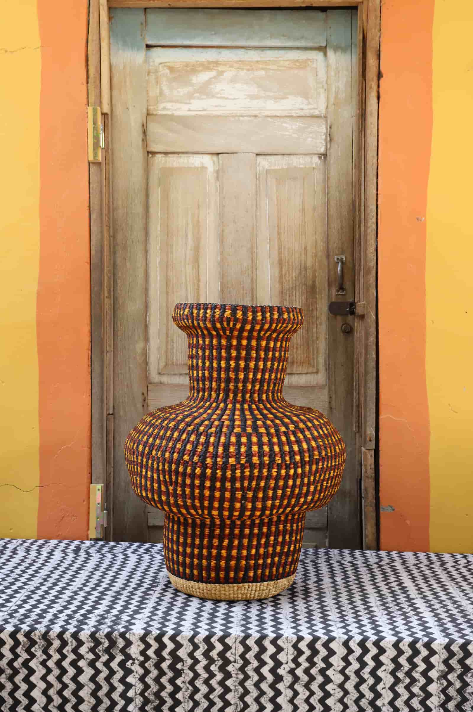 Colorful woven basket on a black and white patterned surface with a wooden door in the background.