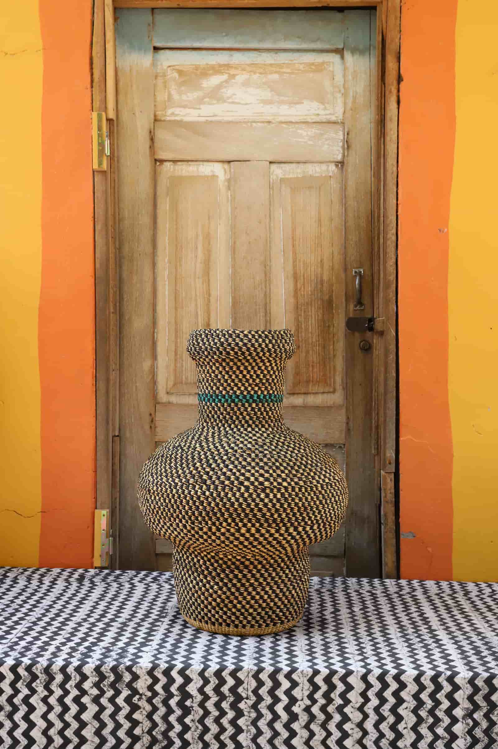 Patterned woven piece on a black and white patterned surface with a wooden door in the background.