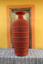 Red woven vase on a checkered tablecloth with a yellow wall and wooden door in the background
