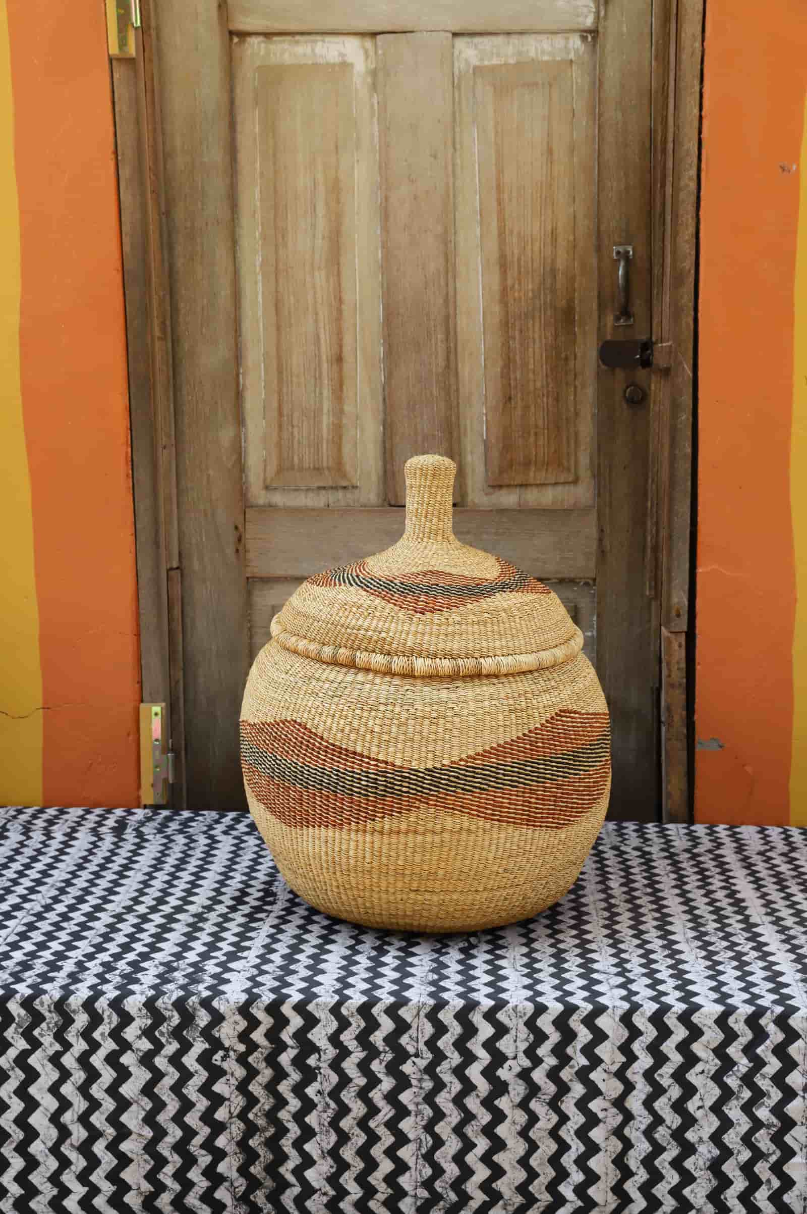 Woven storage basket with colorful patterns on a black and white cloth against a wooden door