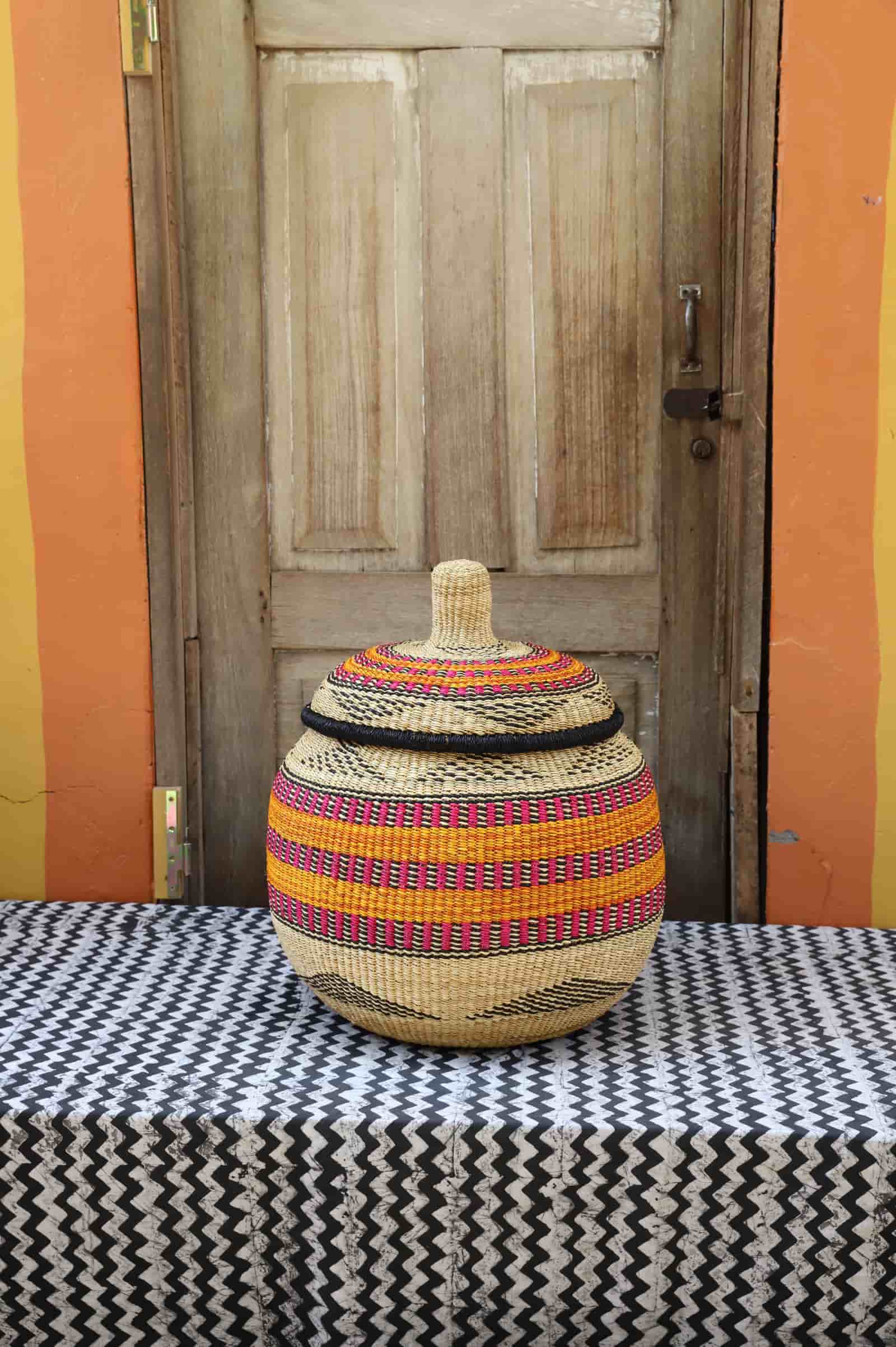 Woven storage basket with colorful patterns on a black and white cloth against a wooden door