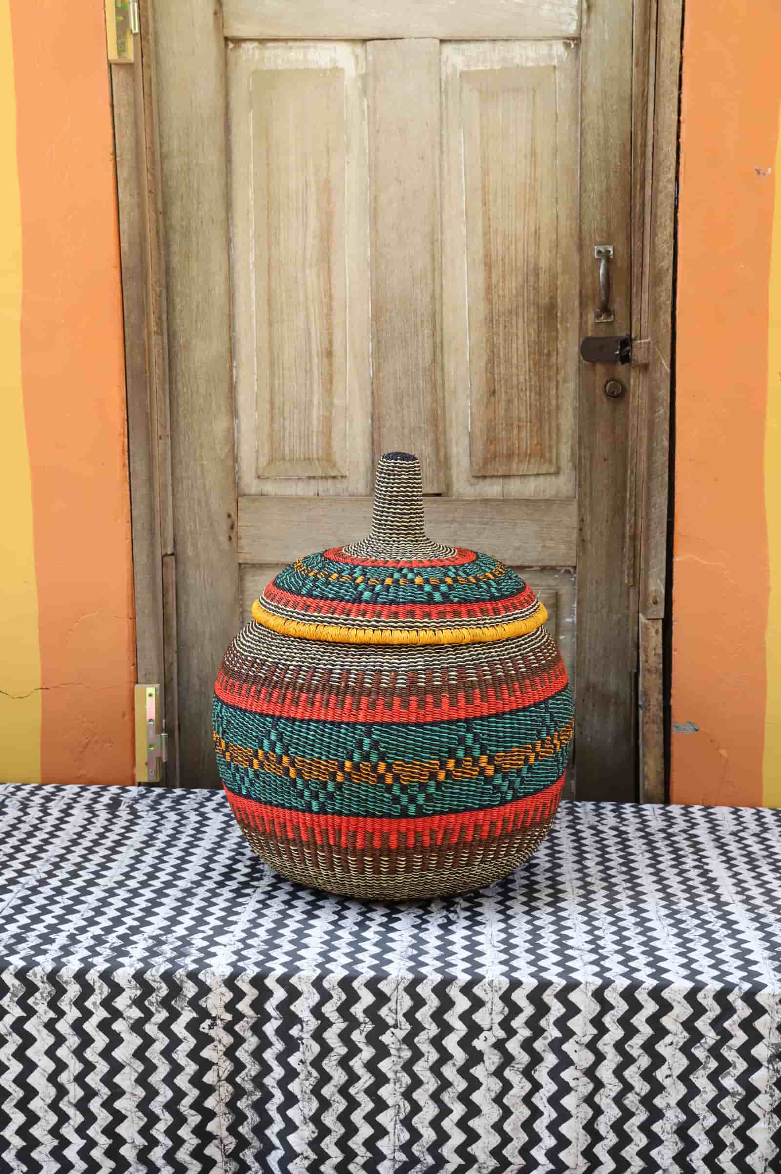 Woven storage basket with colorful patterns on a black and white cloth against a wooden door
