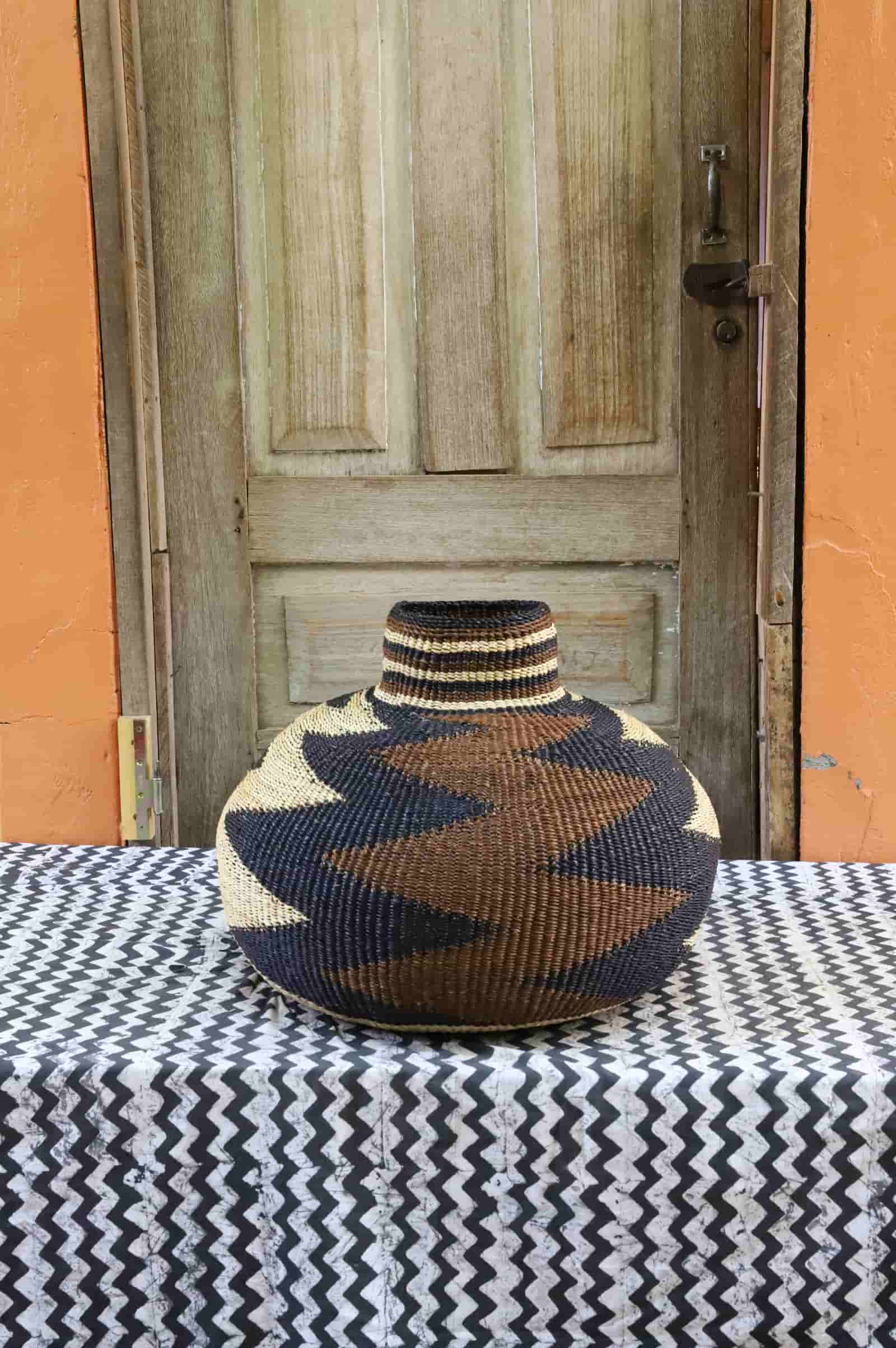 Woven décor with a beautiful pattern on a black and white cloth against a wooden door.