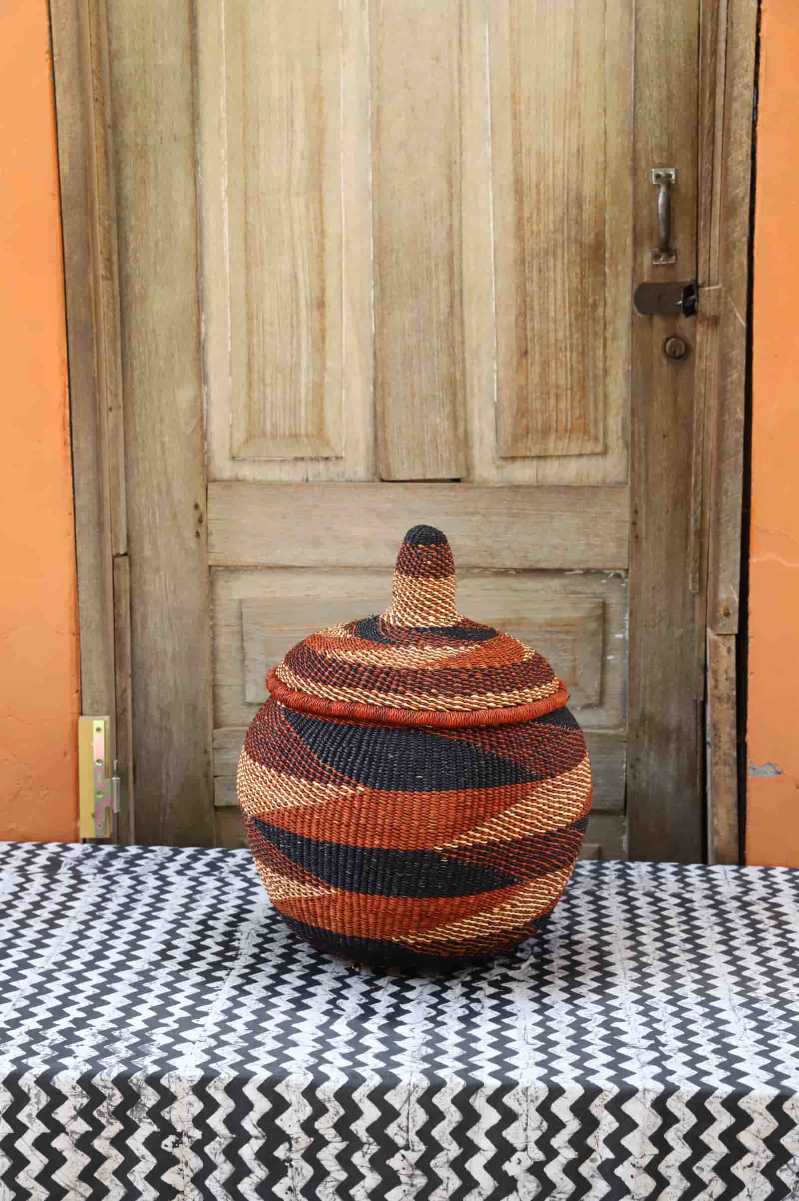 Woven storage basket with colorful patterns on a black and white cloth against a wooden door