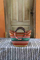 Woven basket with colorful pattern on a table in front of a wooden door.