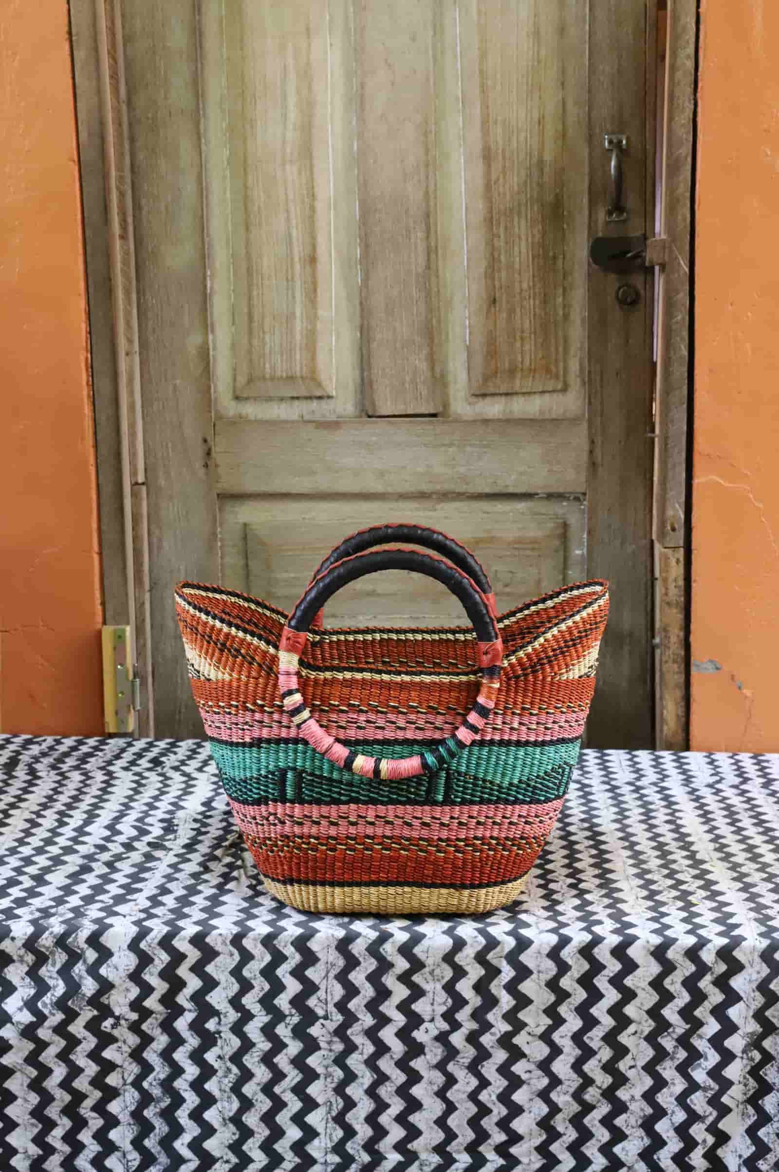 Woven basket with colorful pattern on a table in front of a wooden door.